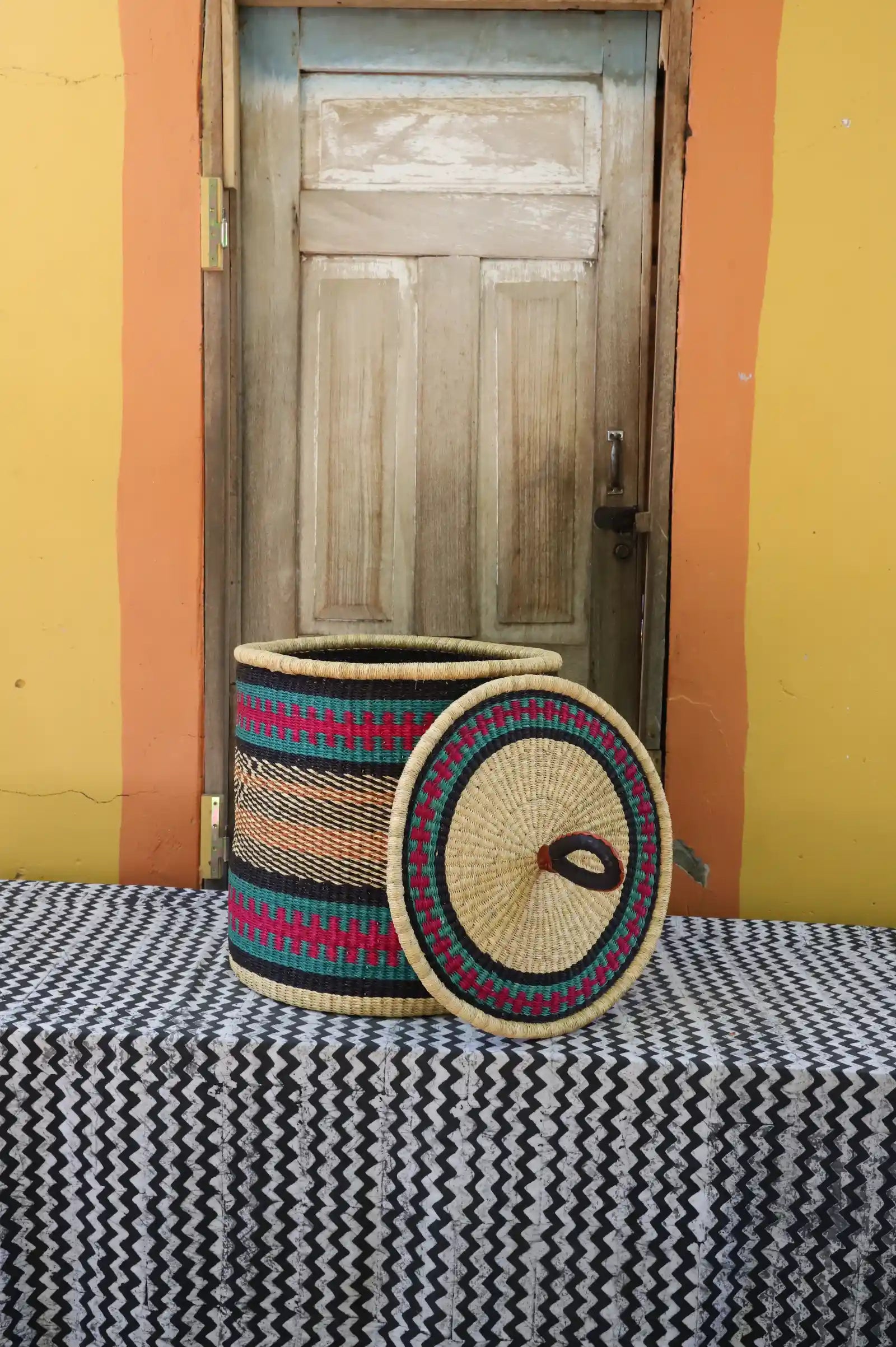 Handwoven Bolga laundry basket with lid removed, natural body with fine multicolour bands and coiled lid.