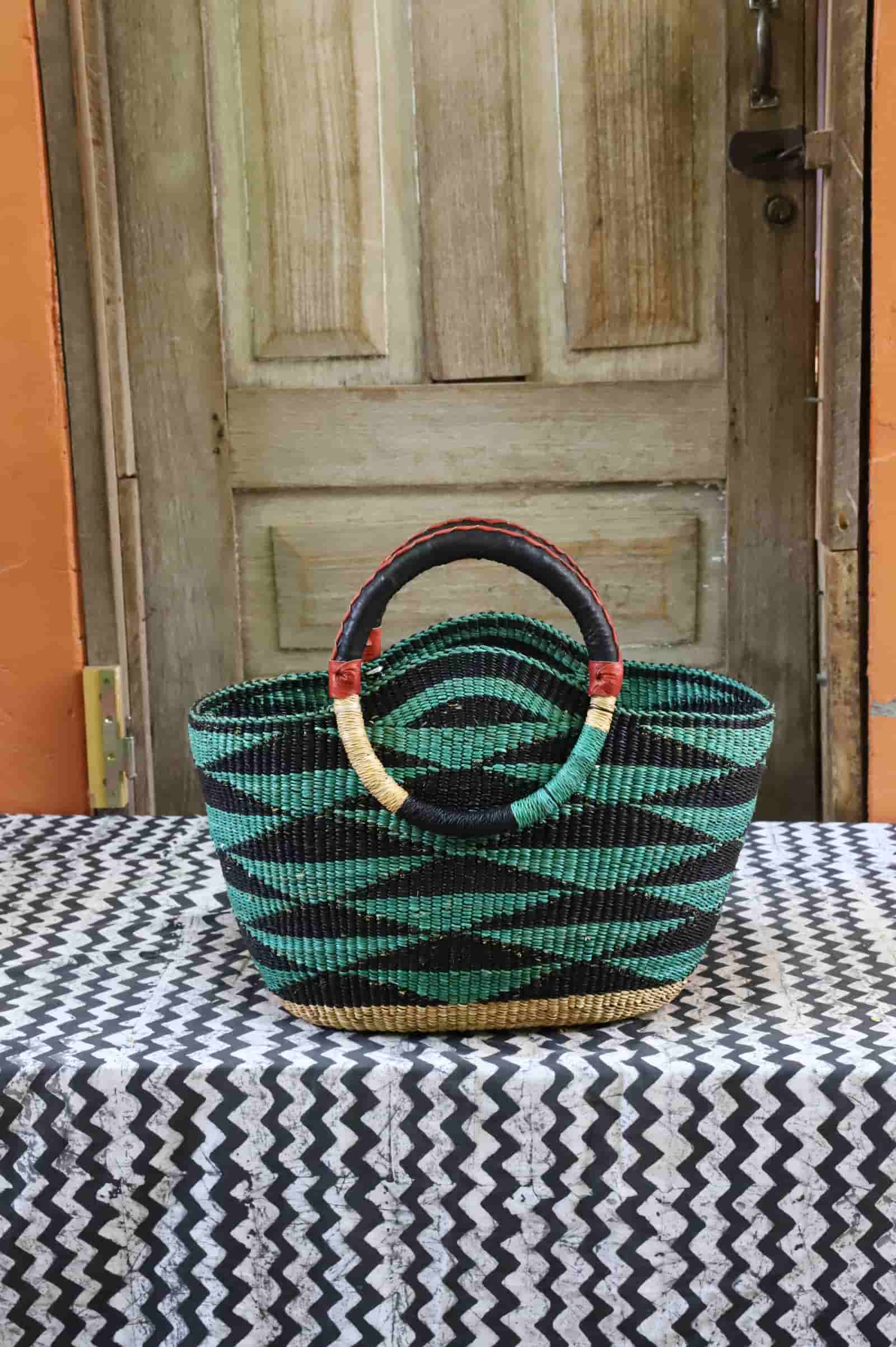 Colorful woven carry on bag with premium leather handles on a black and white cloth against a wooden door.
