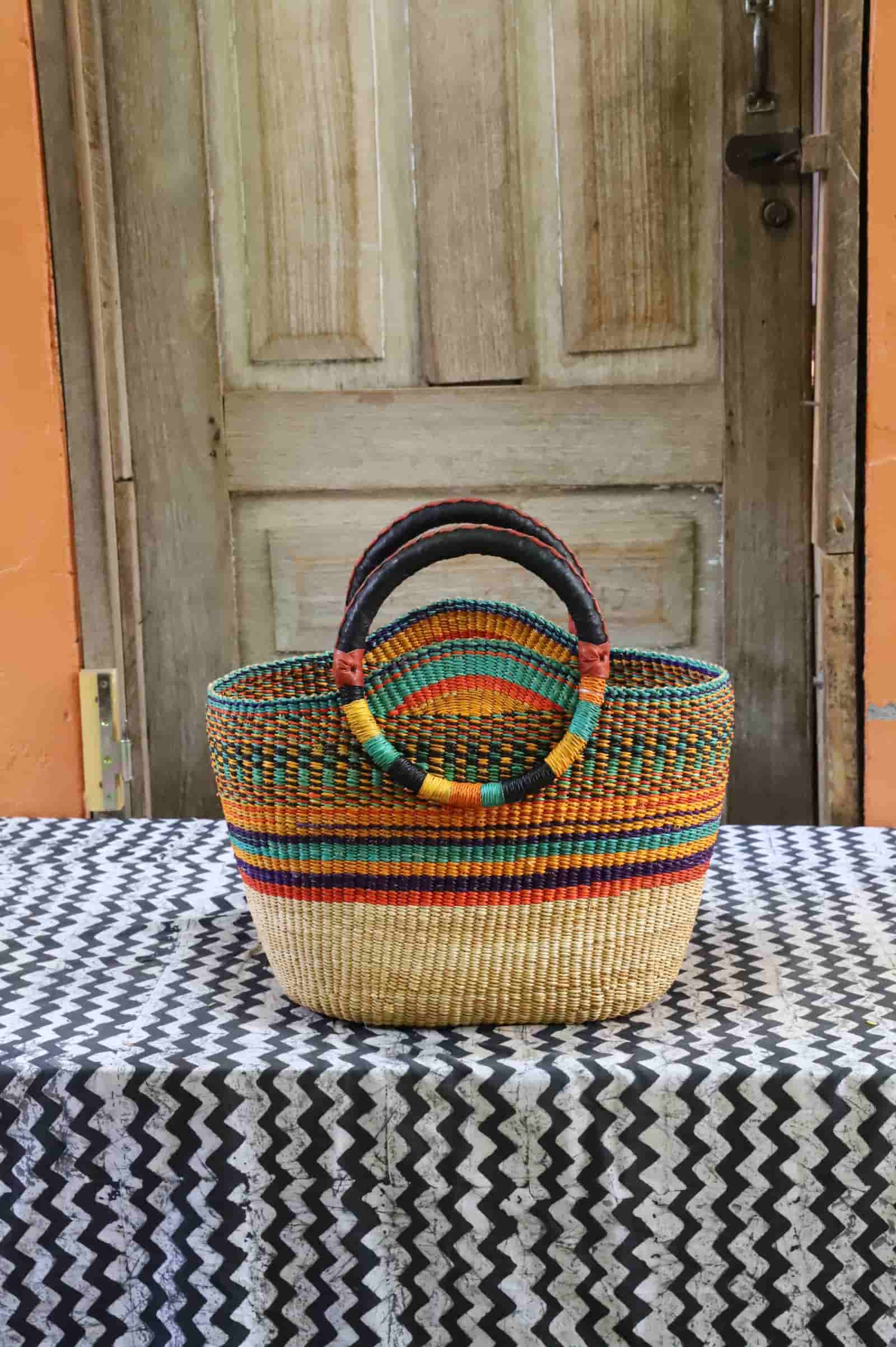 Colorful woven basket on a black and white patterned tablecloth with a wooden door in the background.