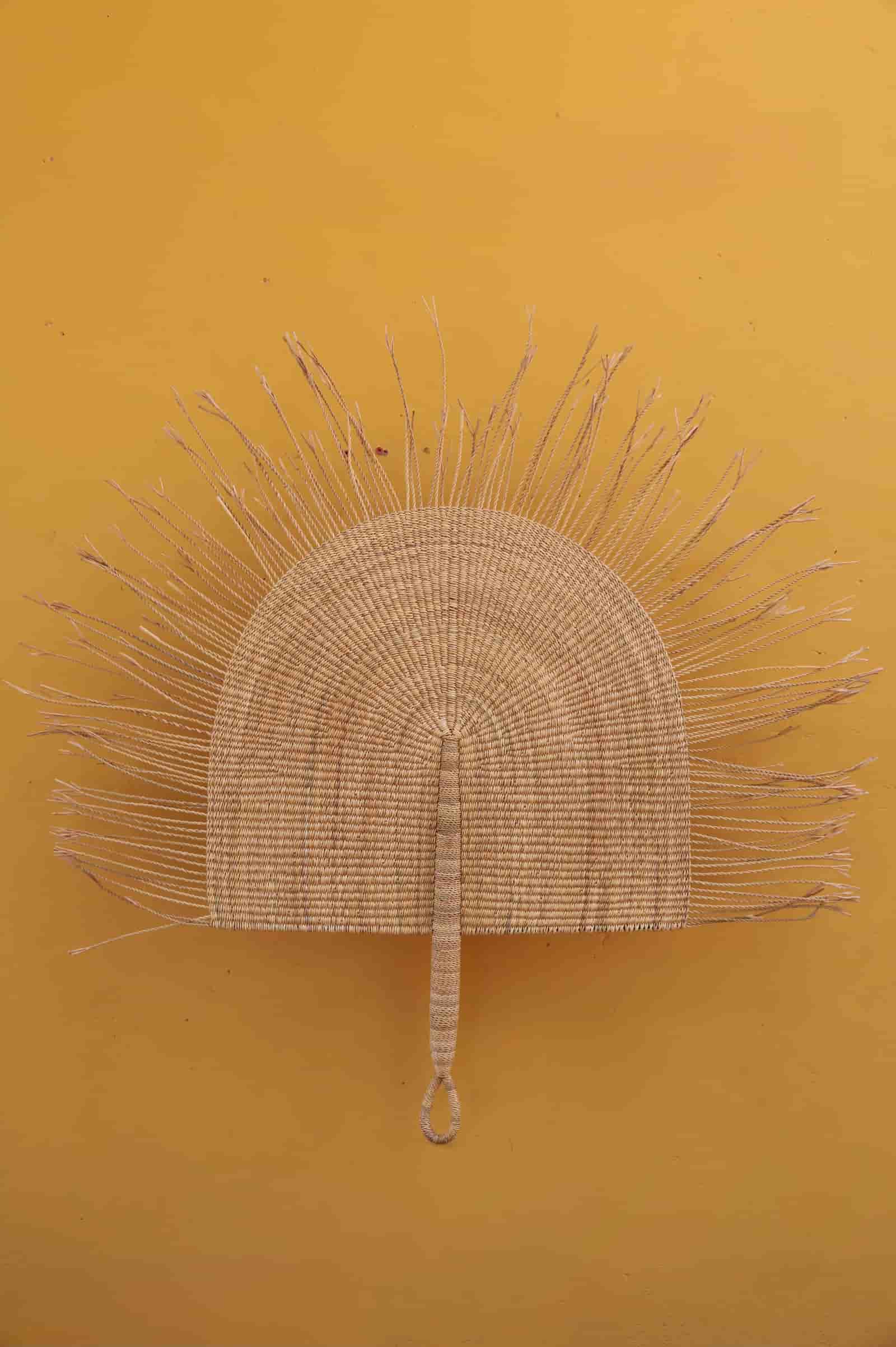 Woven wall art piece against a yellow background