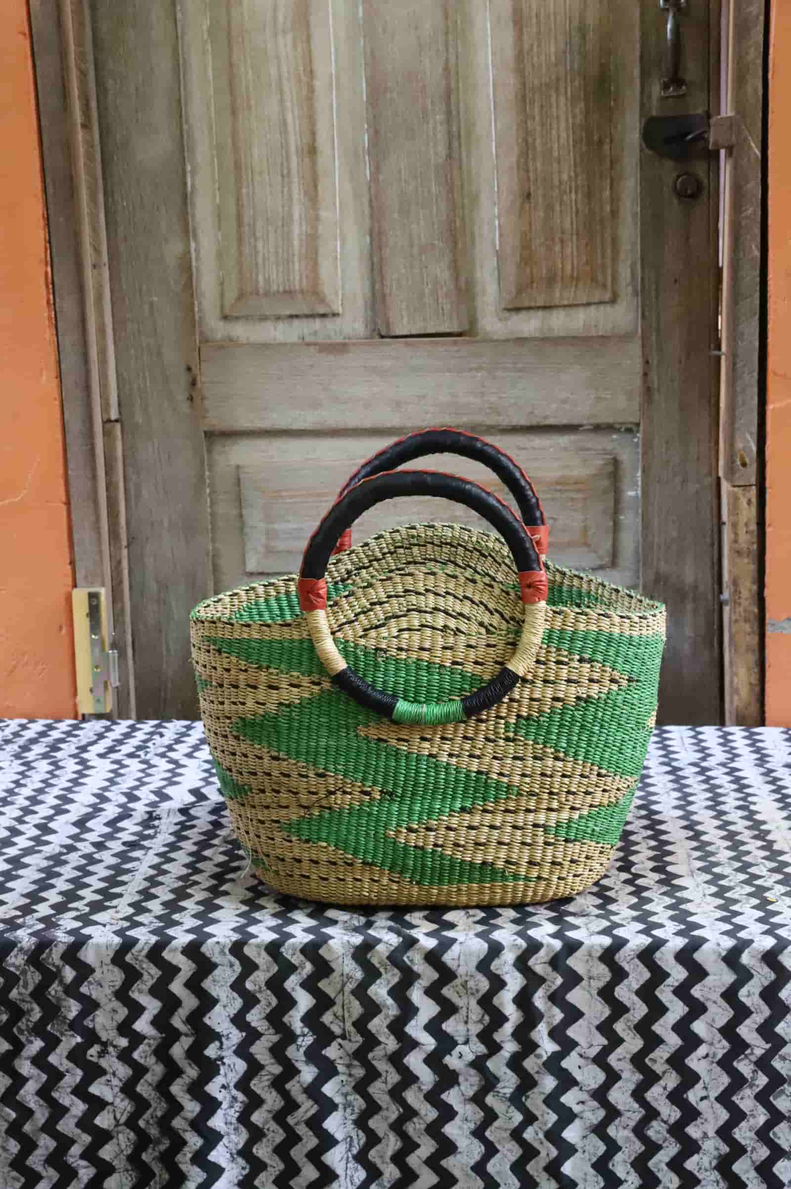 Colorful woven carry on bag with premium leather handles on a black and white cloth against a wooden door.