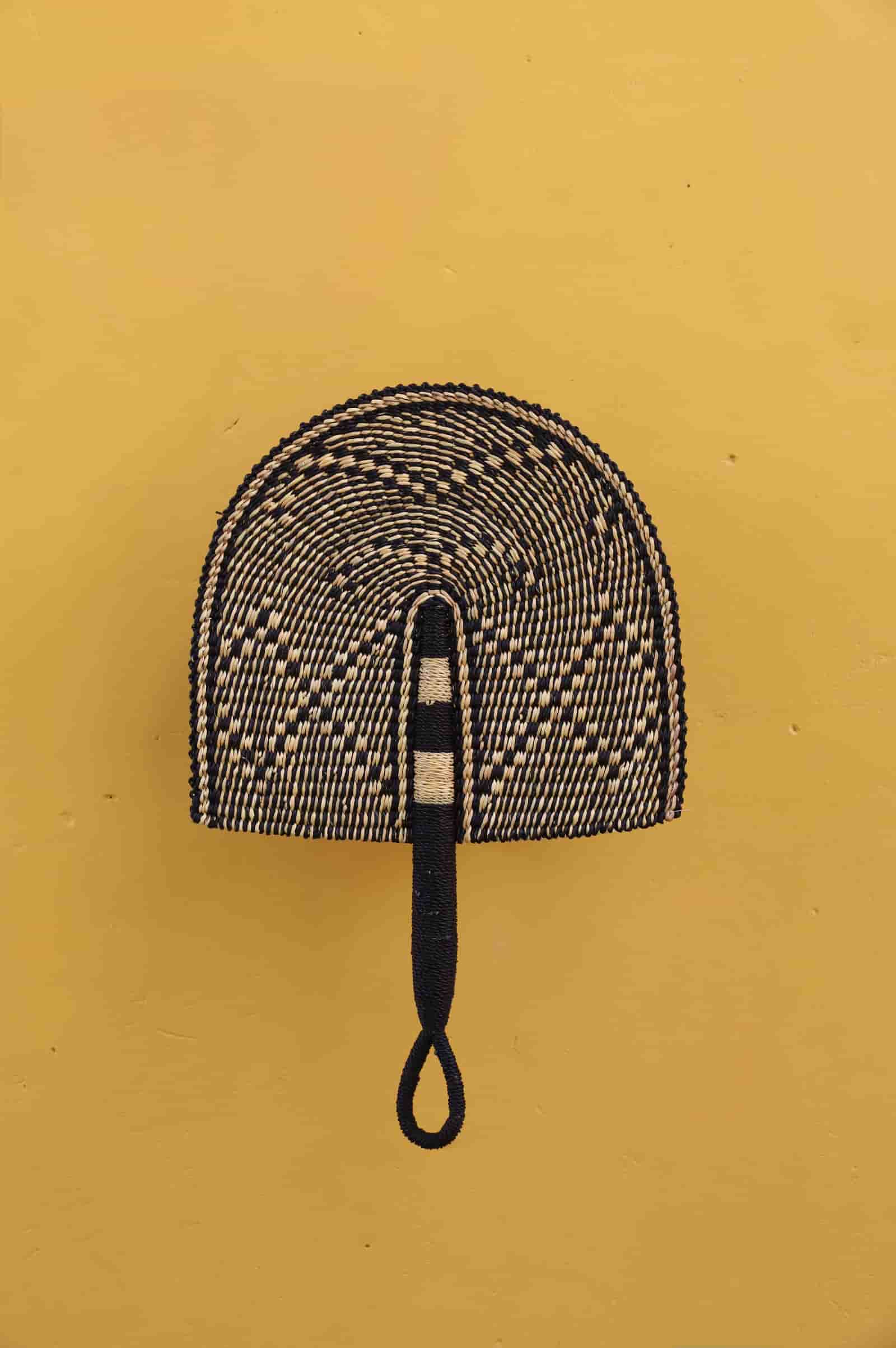 Decorative fan with a patterned head on a yellow background