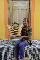 Person holding a woven basket in front of a wooden door with a yellow wall.