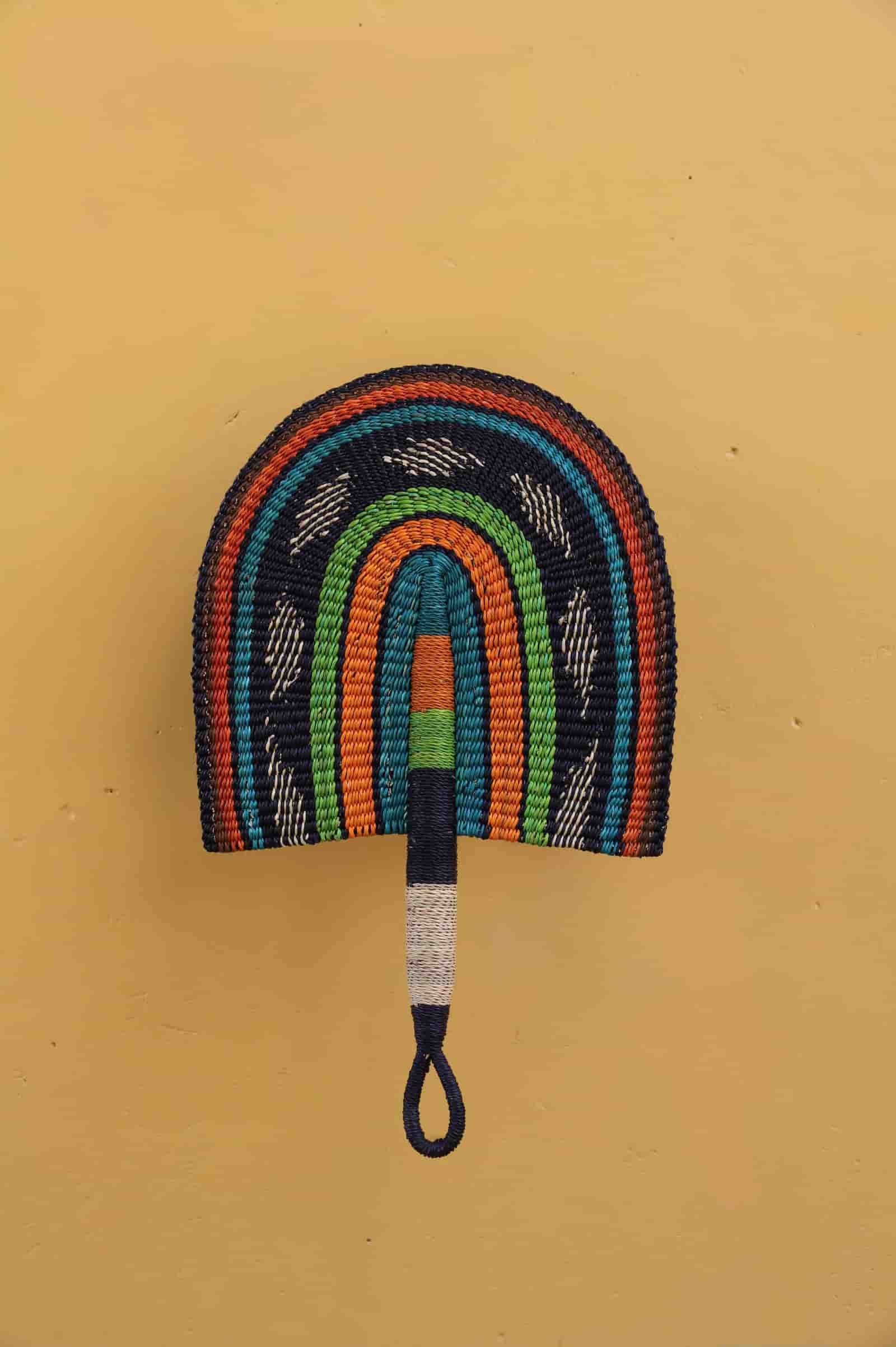 Colorful woven fan with a handle on a yellow background