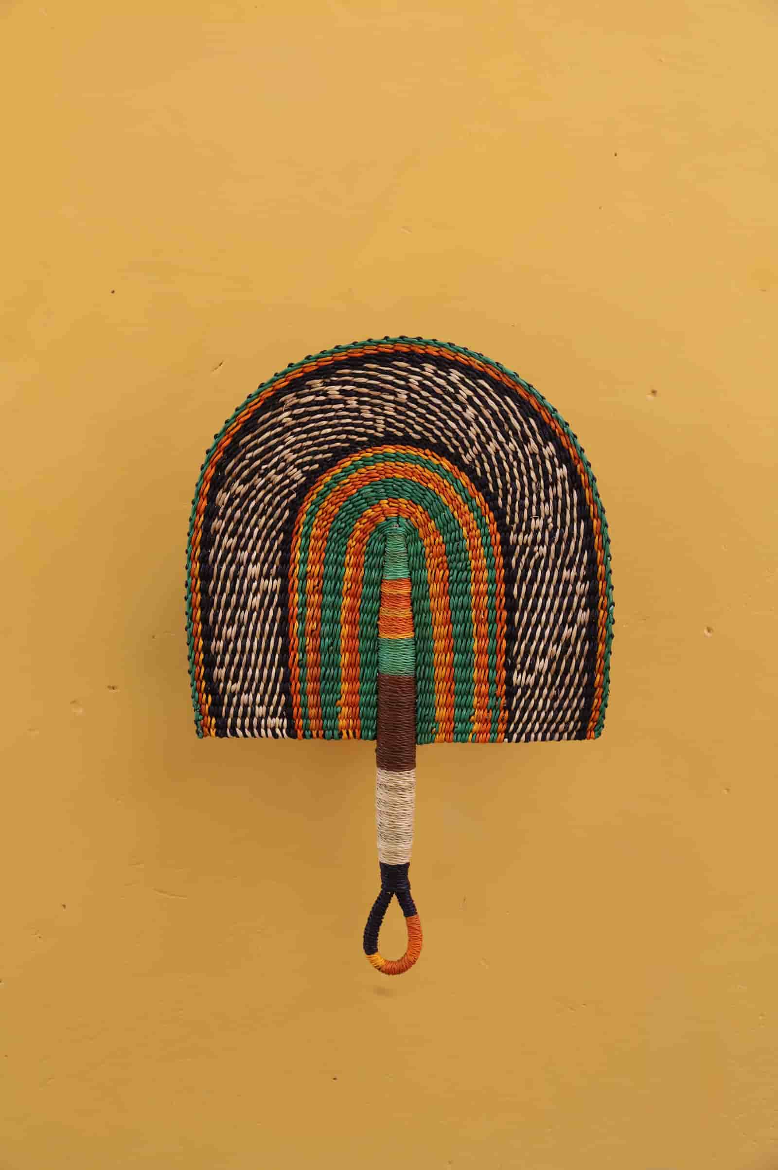 Decorative fan with rainbow pattern on a mustard yellow background