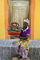 Woman sitting on a bench with a colorful woven basket in a vibrant setting