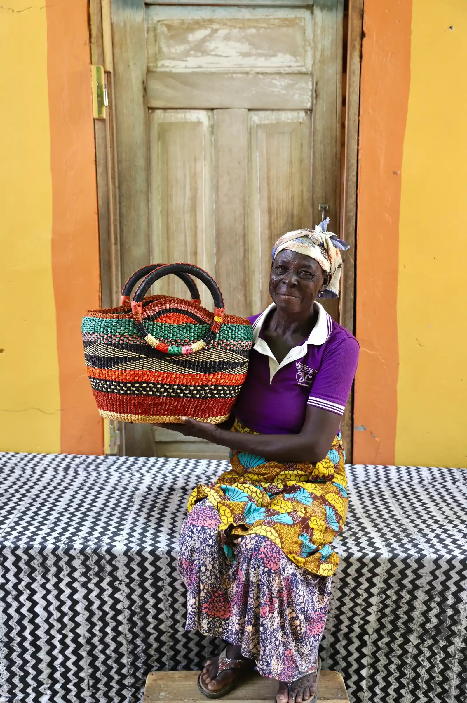 Woman sitting on a bench with a colorful woven basket in a vibrant setting
