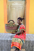 Woman holding a woven basket in front of a colorful wall.
