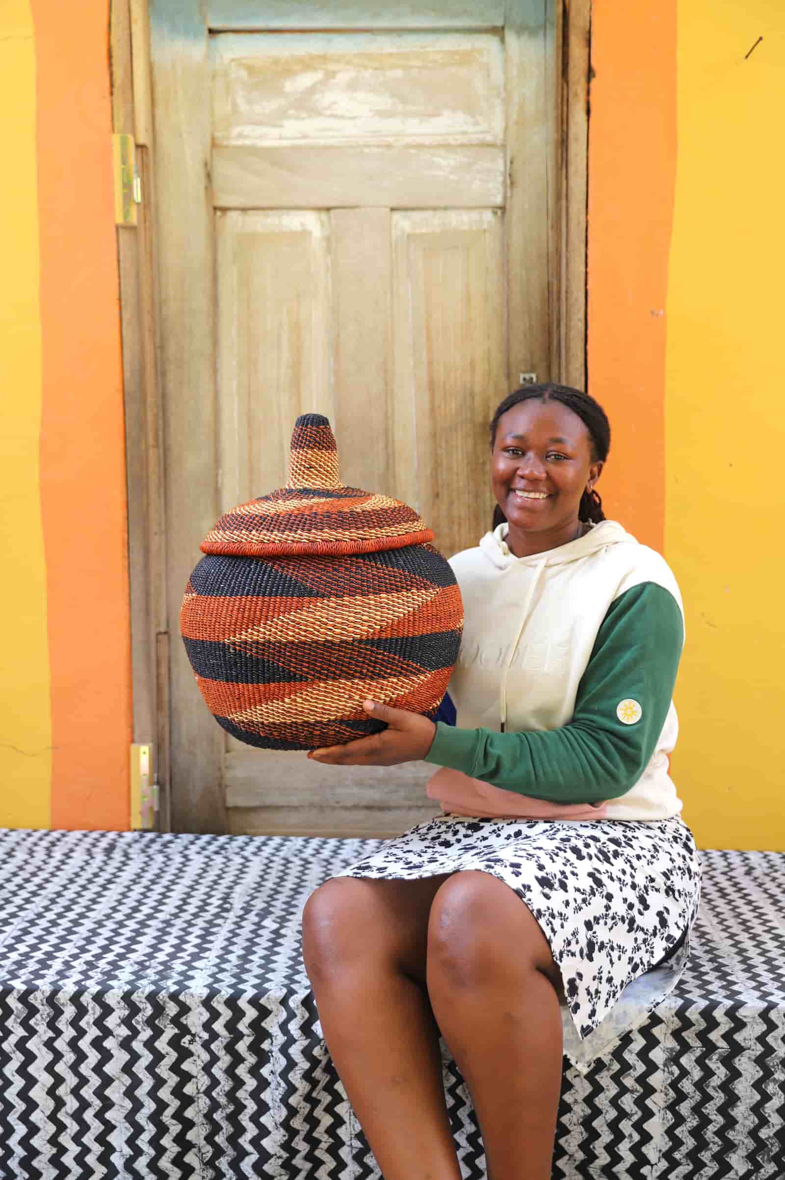 Woman holding medium Orbit storage basket in rust and black diagonal stripe