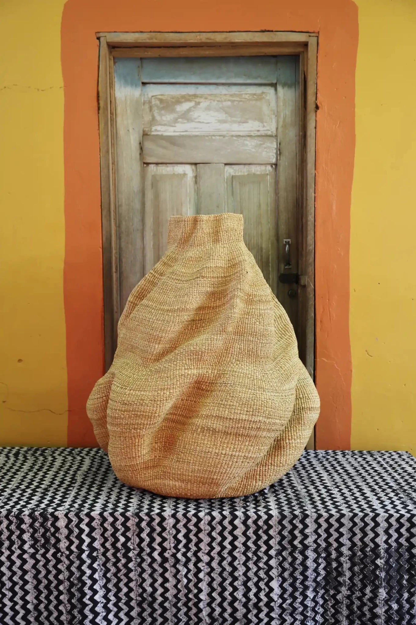 Decorative basket  on a black and white cloth against a wooden door.