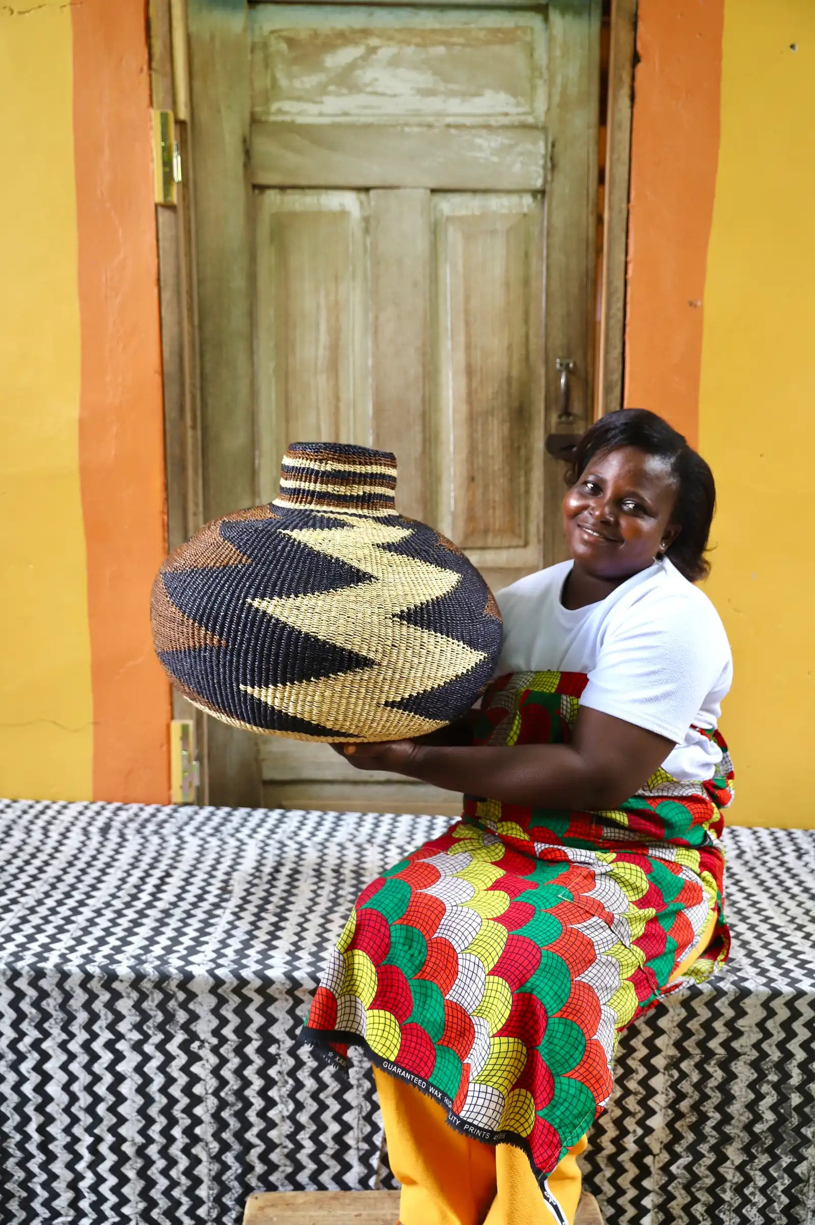 Woman holding a beautiful basket on a black and white cloth against a colorful background