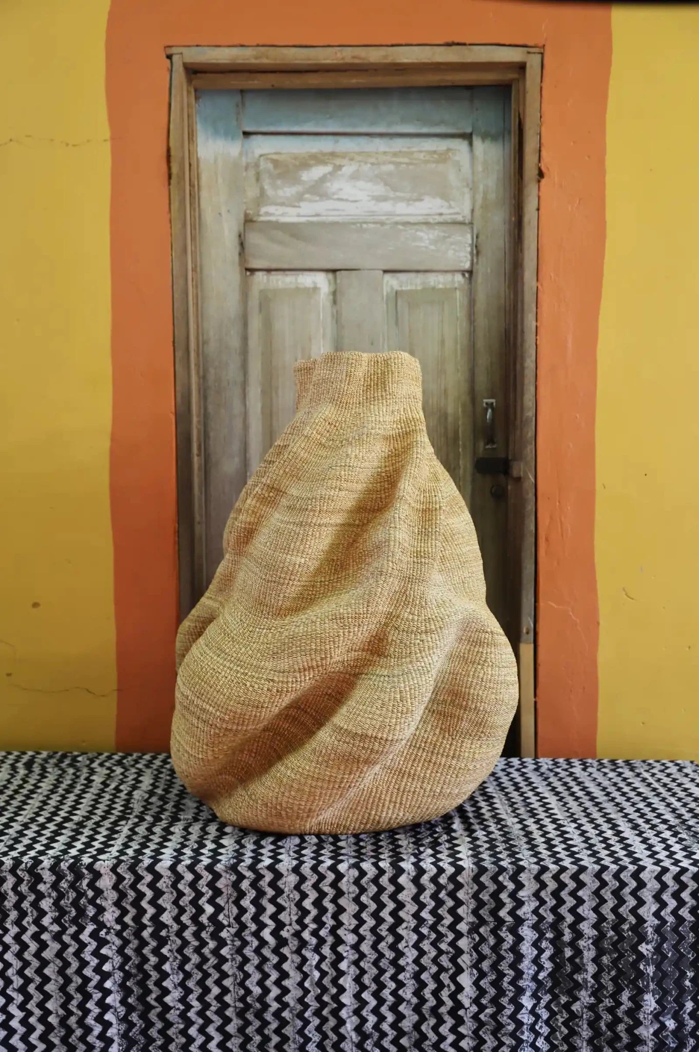 Decorative basket  on a black and white cloth against a wooden door.