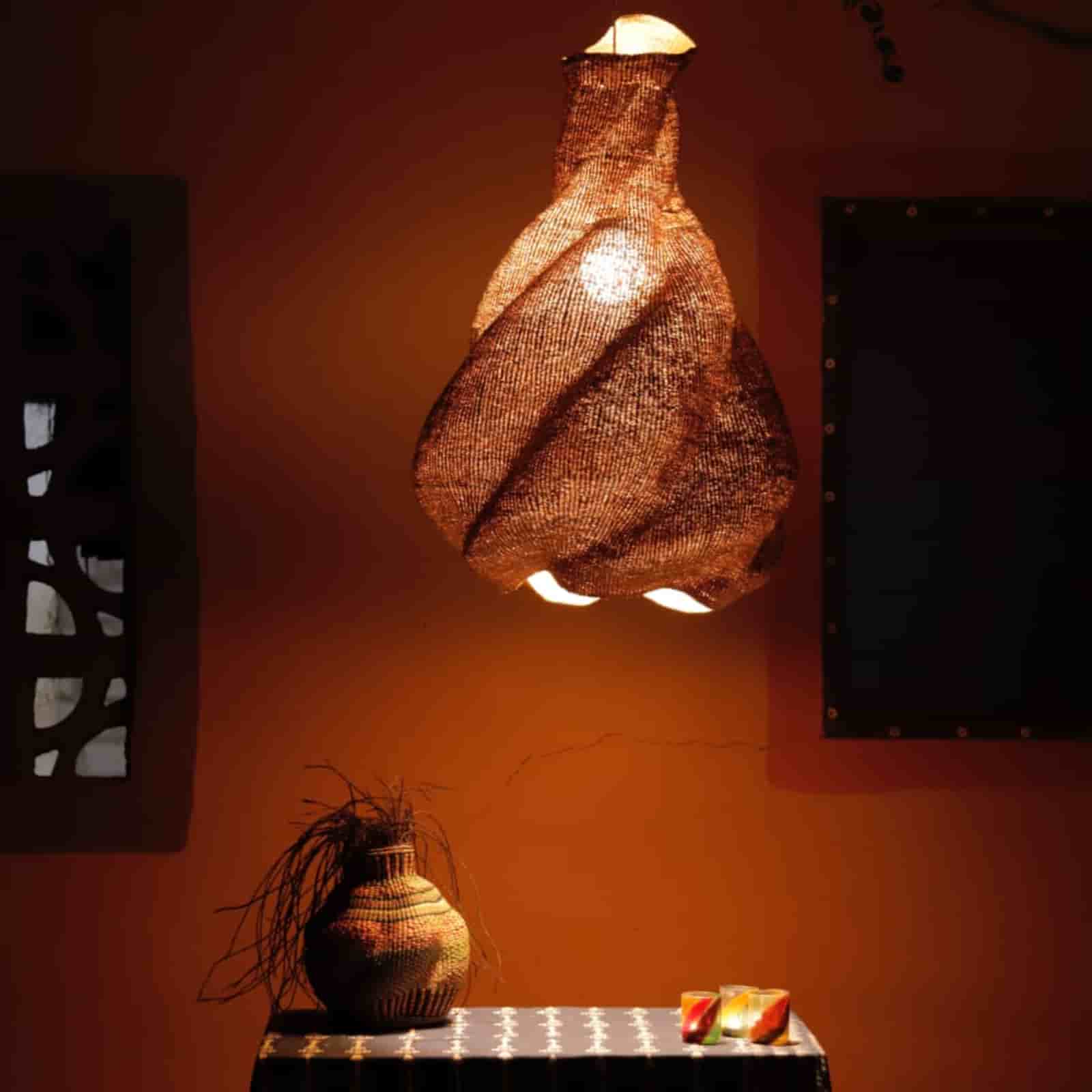 Woven lamp hanging on an orange wall with decorative elements below.