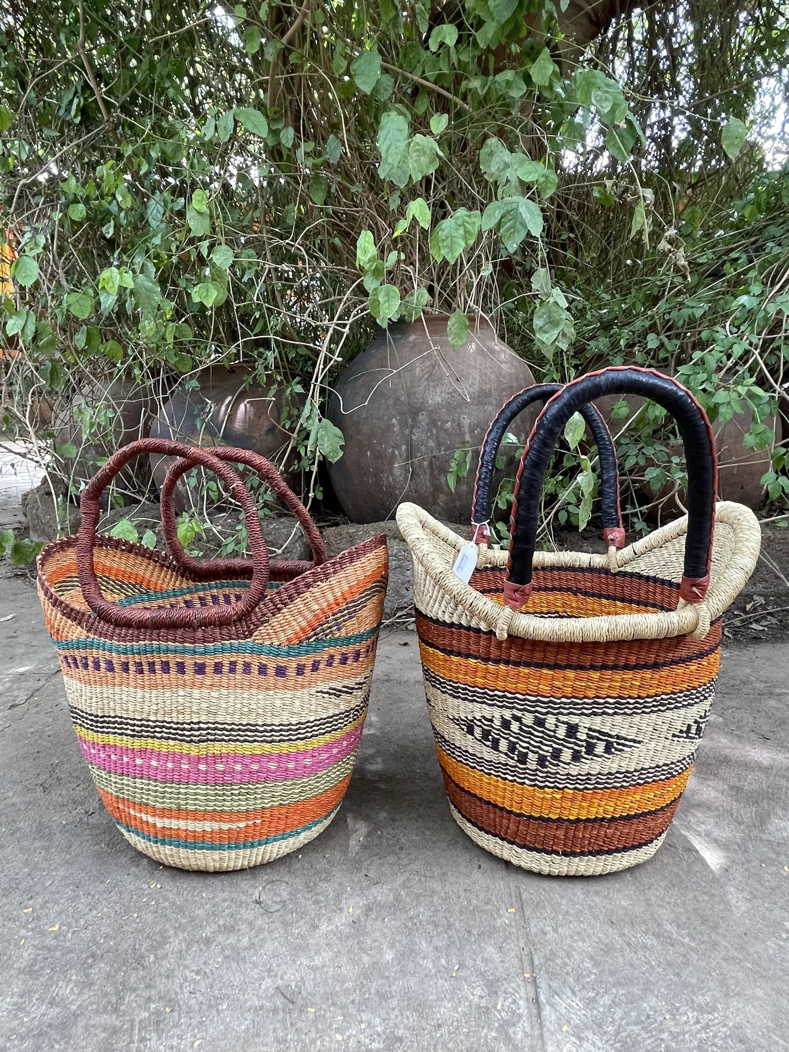 Two two-handled baskets side by side: exposed straw handles on the left and leather-covered handles on the right.
