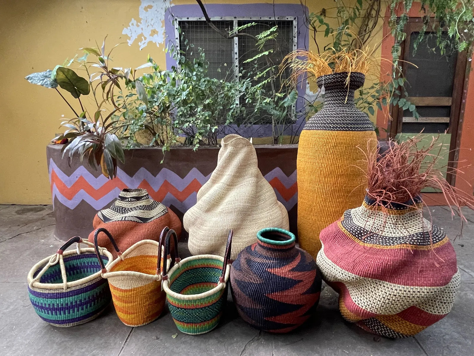 Round handled shopping baskets arranged with larger and sculptural woven forms.