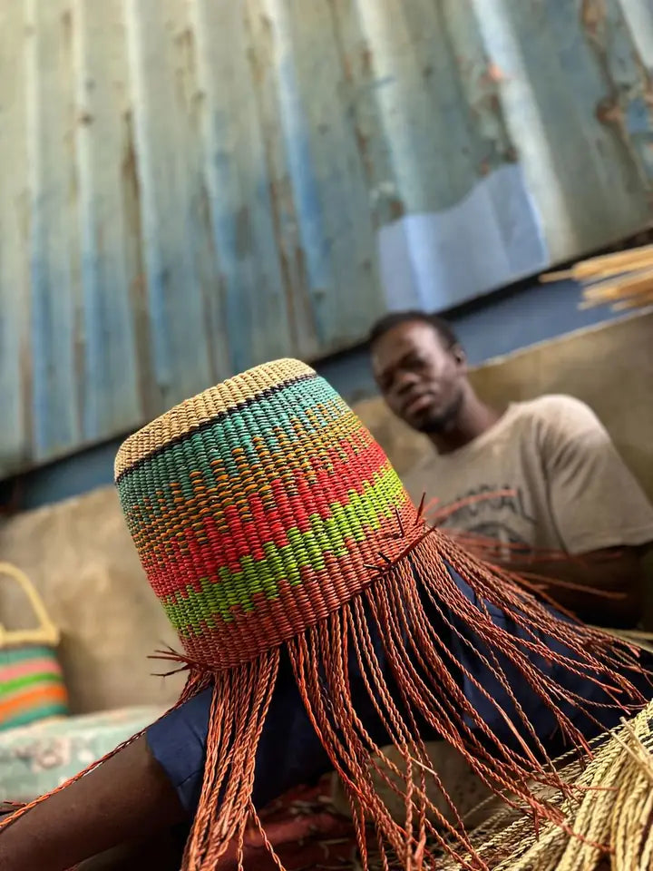 A basket maker weaving the rising sides of a colourful basket