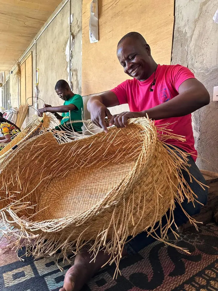 A basket maker finishing the edge of a natural straw basket