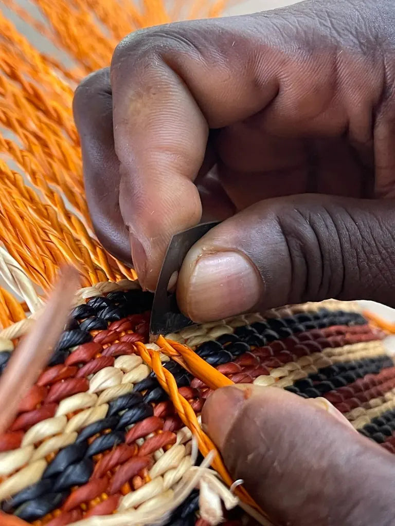 Close view of hands trimming the edge of a colourful woven basket