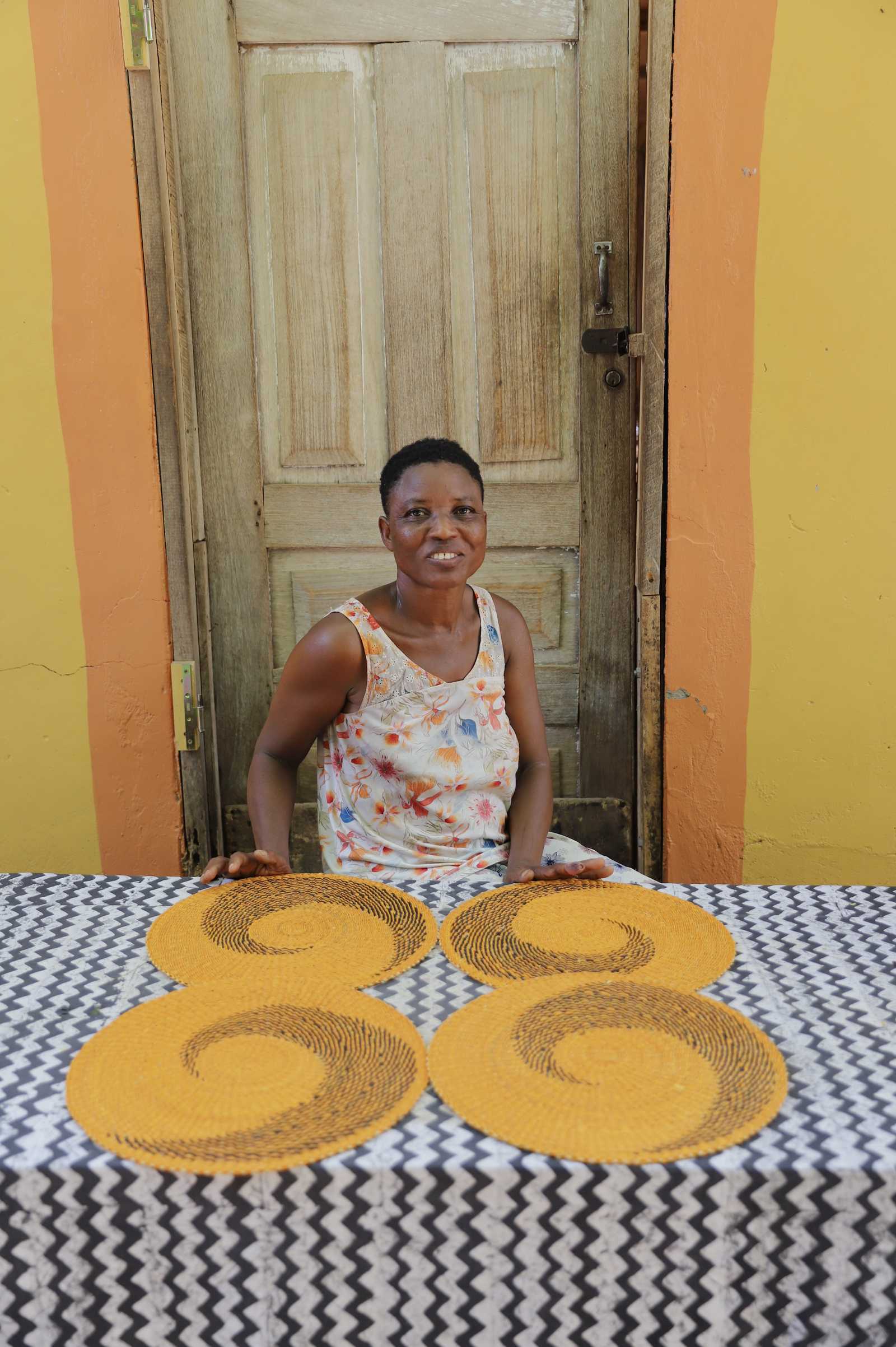 Two handwoven Bolga placemats in natural straw with black spiral pattern, displayed by their maker in Bolgatanga, Ghana.