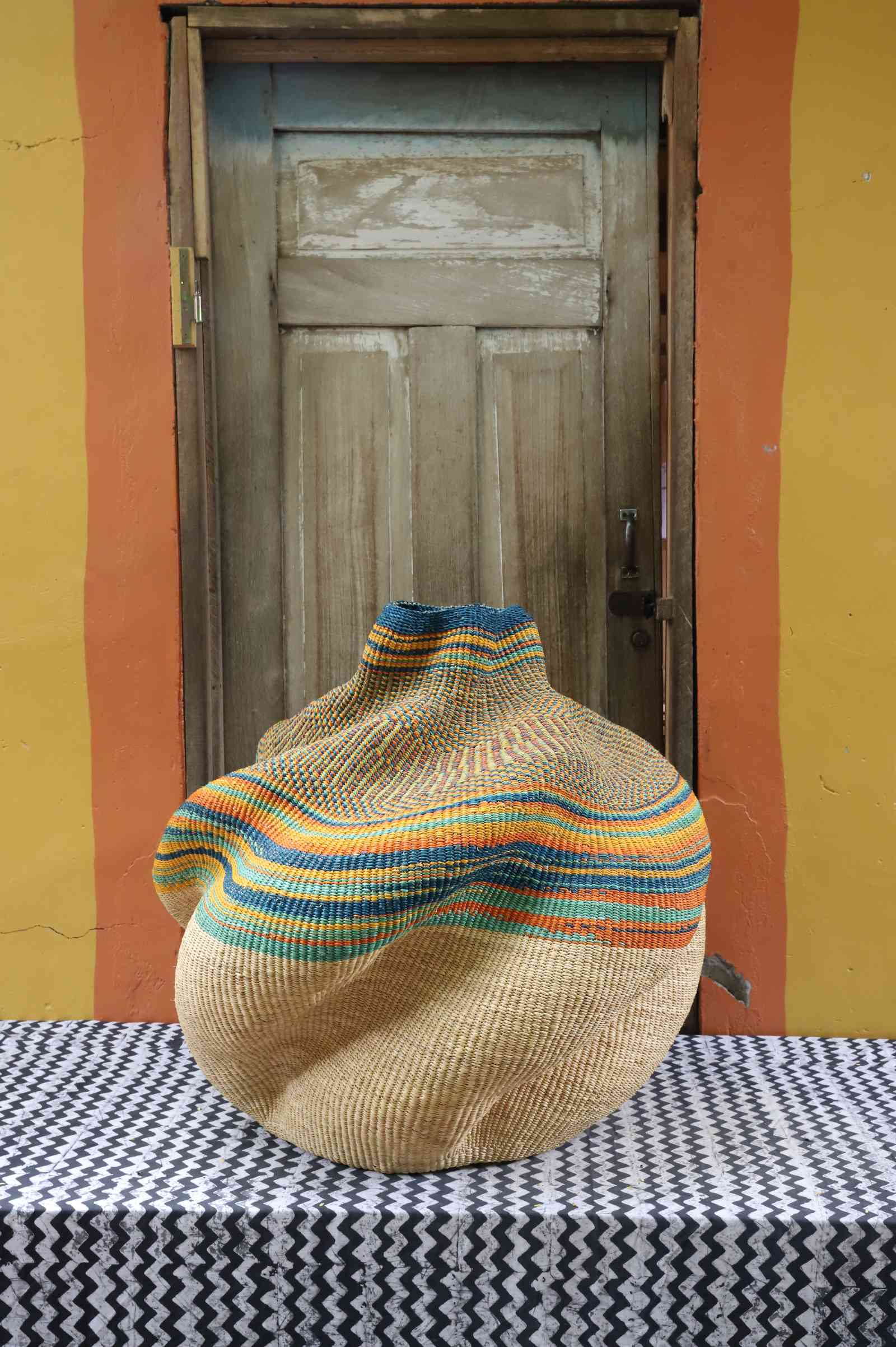 Large handwoven Bolga art basket in natural straw, side view showing the sculpted lobed pot form.