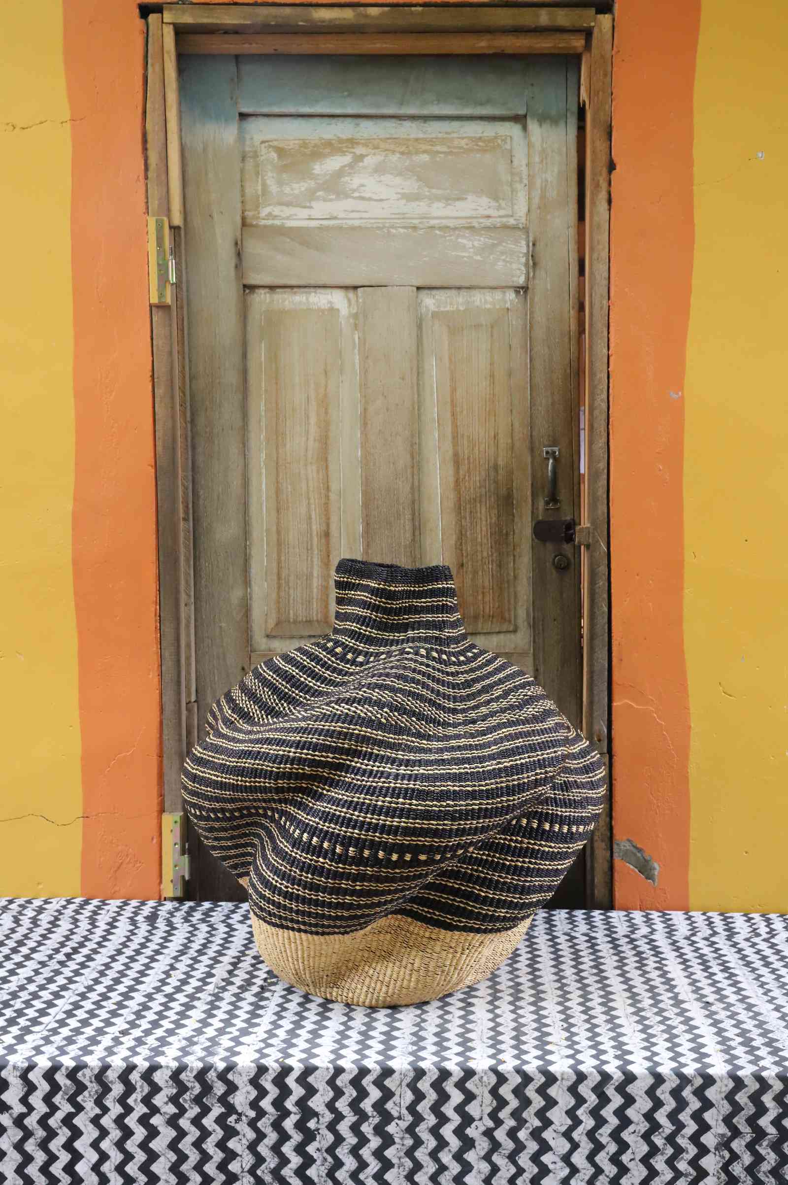 Medium handwoven Bolga art basket in a sculpted pot form, natural straw with dark horizontal banded stripes.