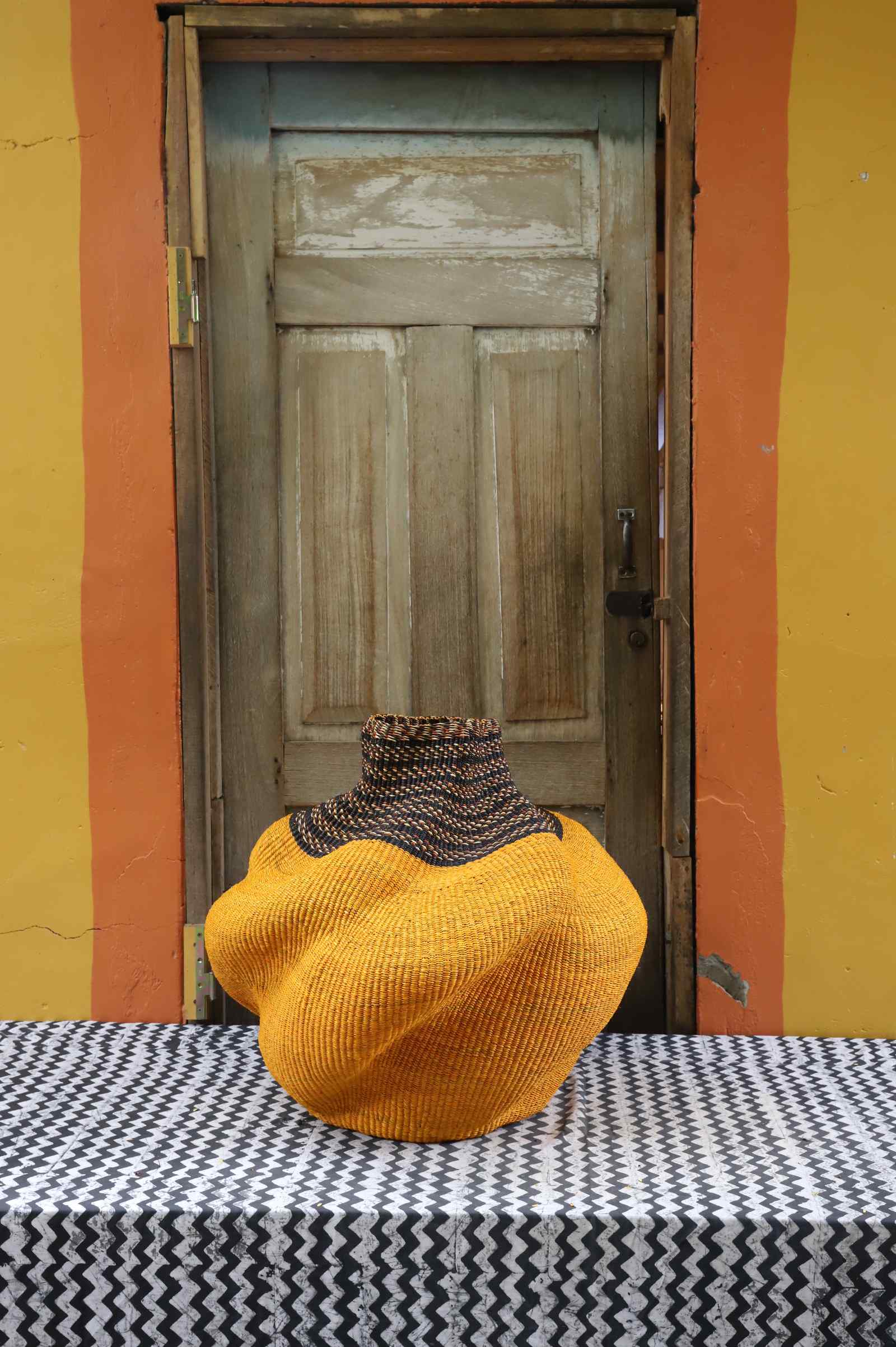 Medium handwoven Bolga art basket in a sculpted mustard-yellow pot with a dark banded neck.