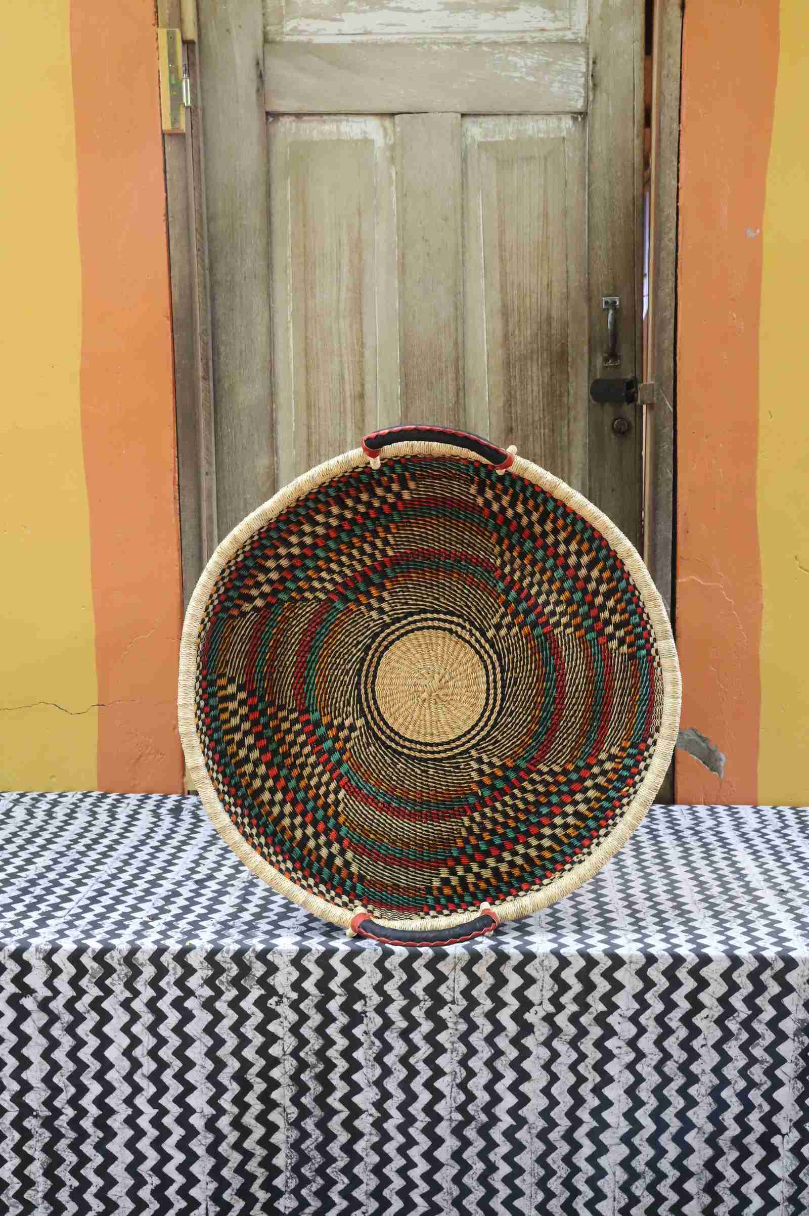 Medium handwoven Bolga wall tray disc in natural straw with fine dark concentric radiating bands.