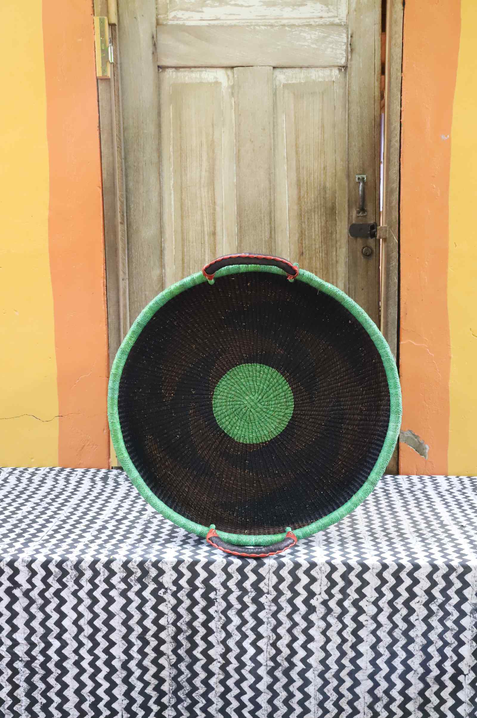 Medium handwoven Bolga wall tray disc in dark elephant grass with a bright green rim and green centre dot.