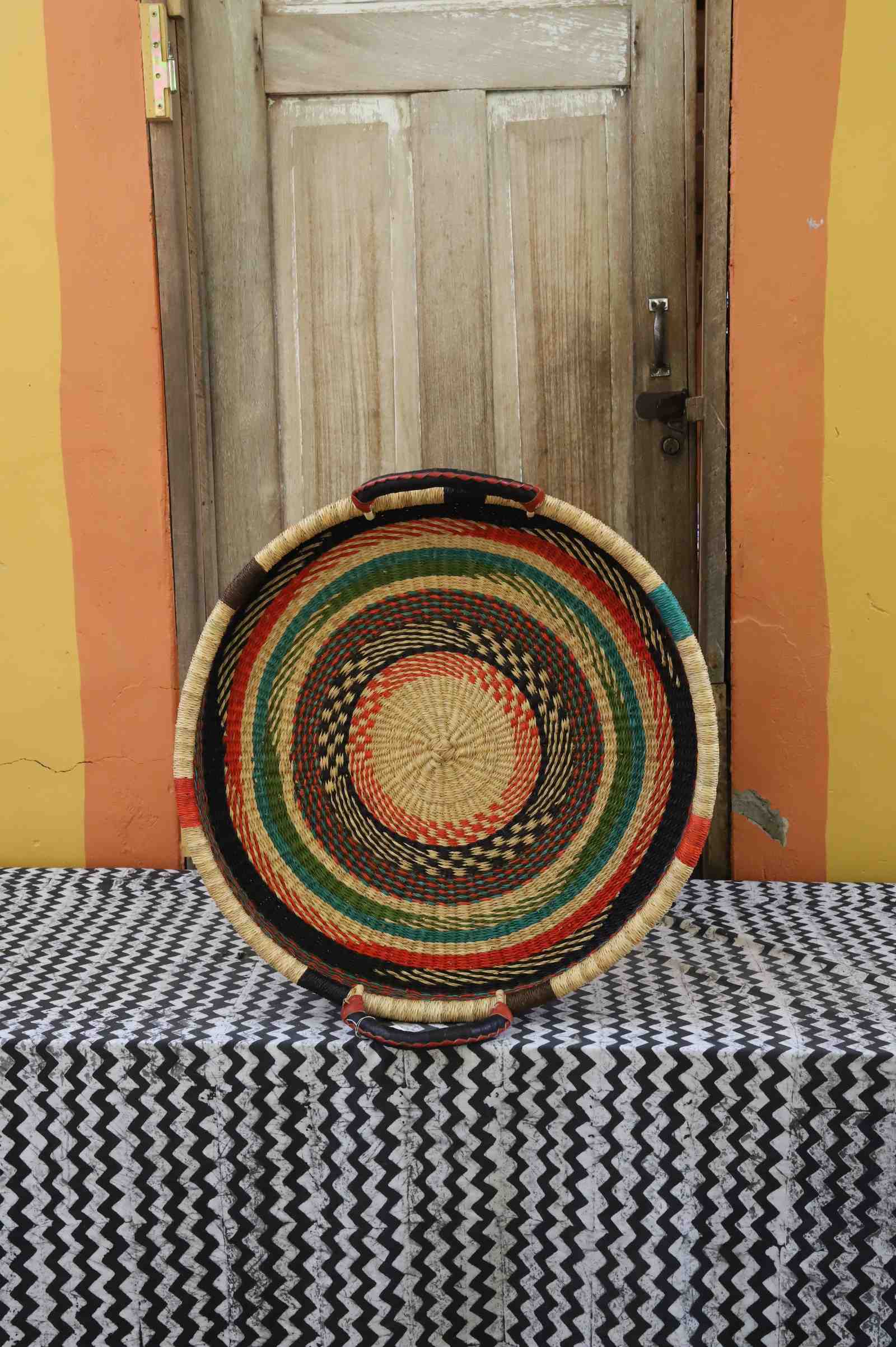 Single-weave handwoven Bolga wall tray disc with red, green and dark concentric bands and yellow centre.
