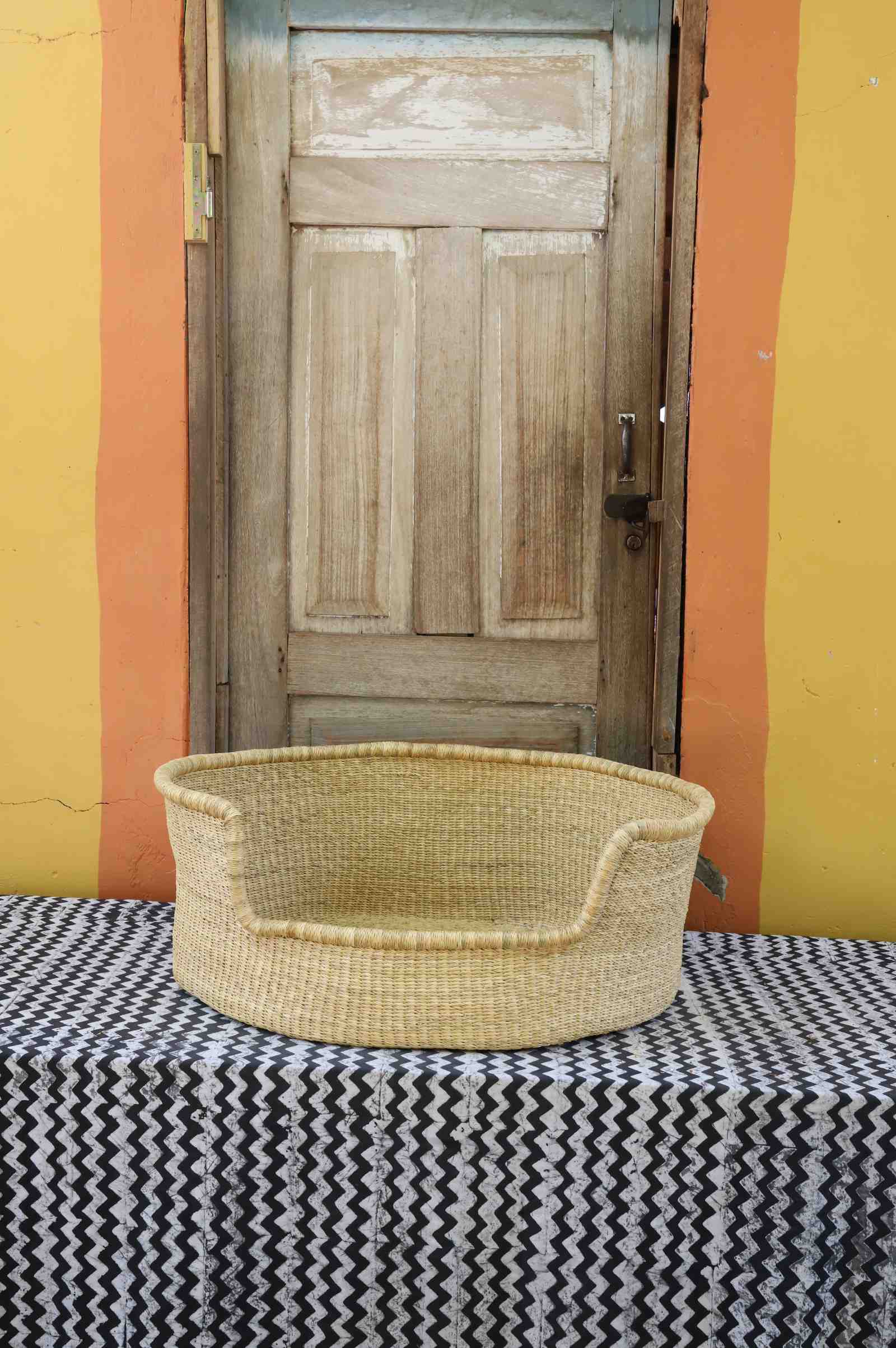 Large handwoven Bolga pet bed in plain natural straw with a fine dark rim detail.