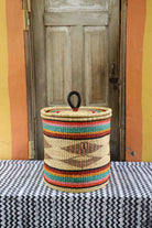 Handwoven Bolga laundry basket with coiled rim and lid in natural straw with fine multicolour bands and central motif.