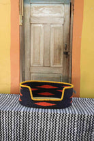 Medium handwoven Bolga pet bed in bold black with orange diamond flames and a yellow banded rim.