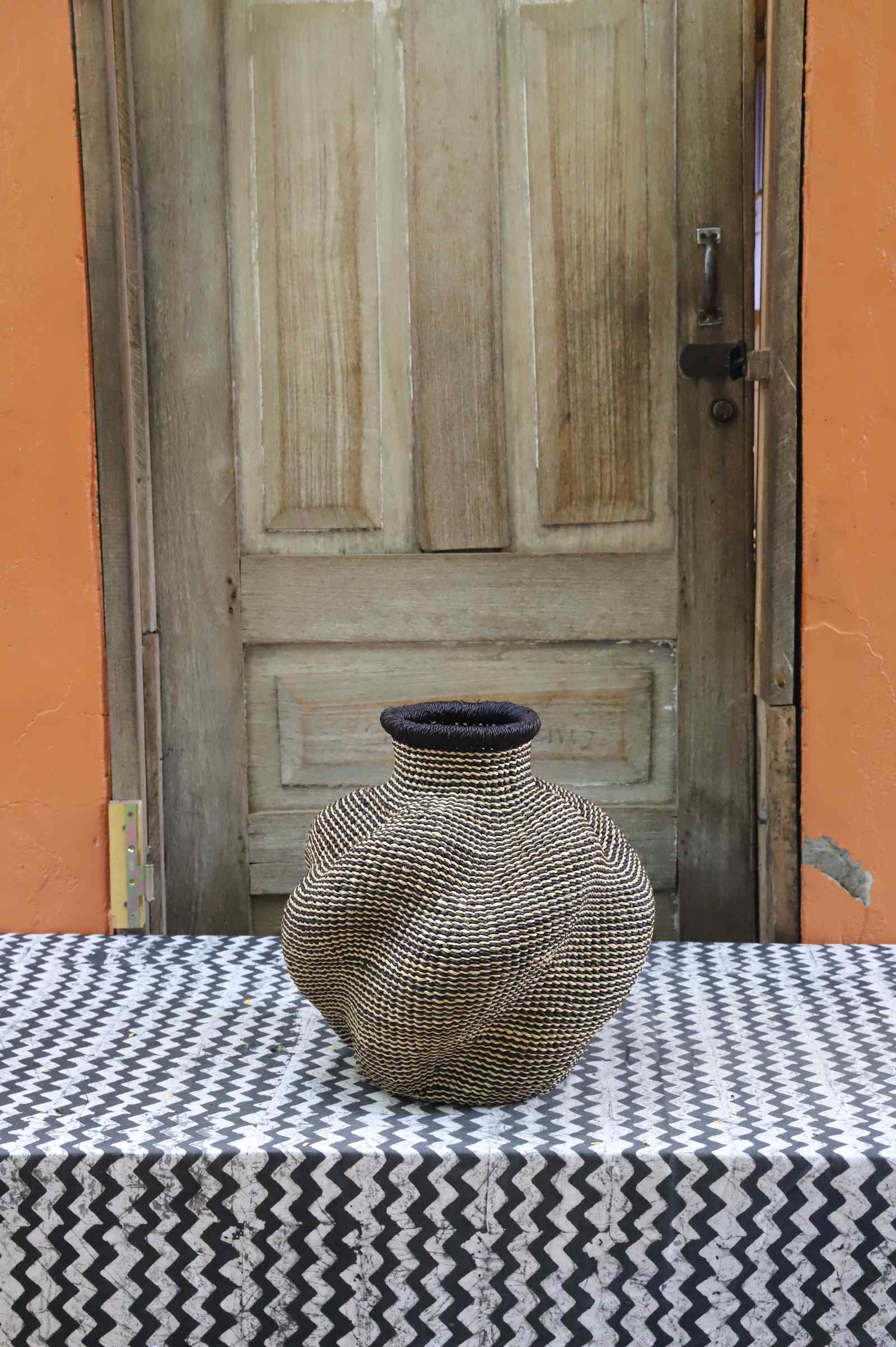 Handwoven Bolga art basket in an urn shape, all natural straw with a tight even weave and dark rim.