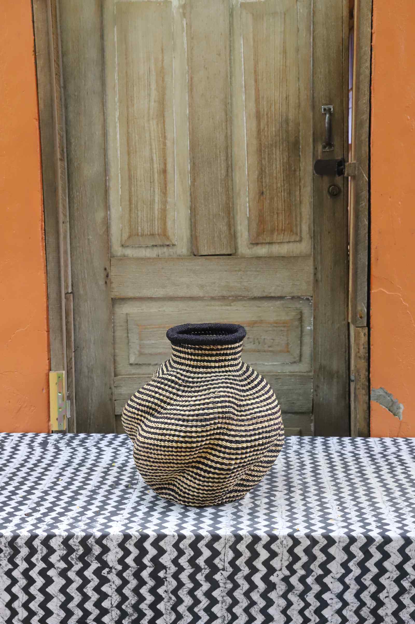 Handwoven Bolga art basket in an urn shape, natural straw with a fine subtle diamond weave.