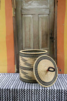 Handwoven Bolga laundry basket with lid removed, natural straw body with fine black banded wave motifs.