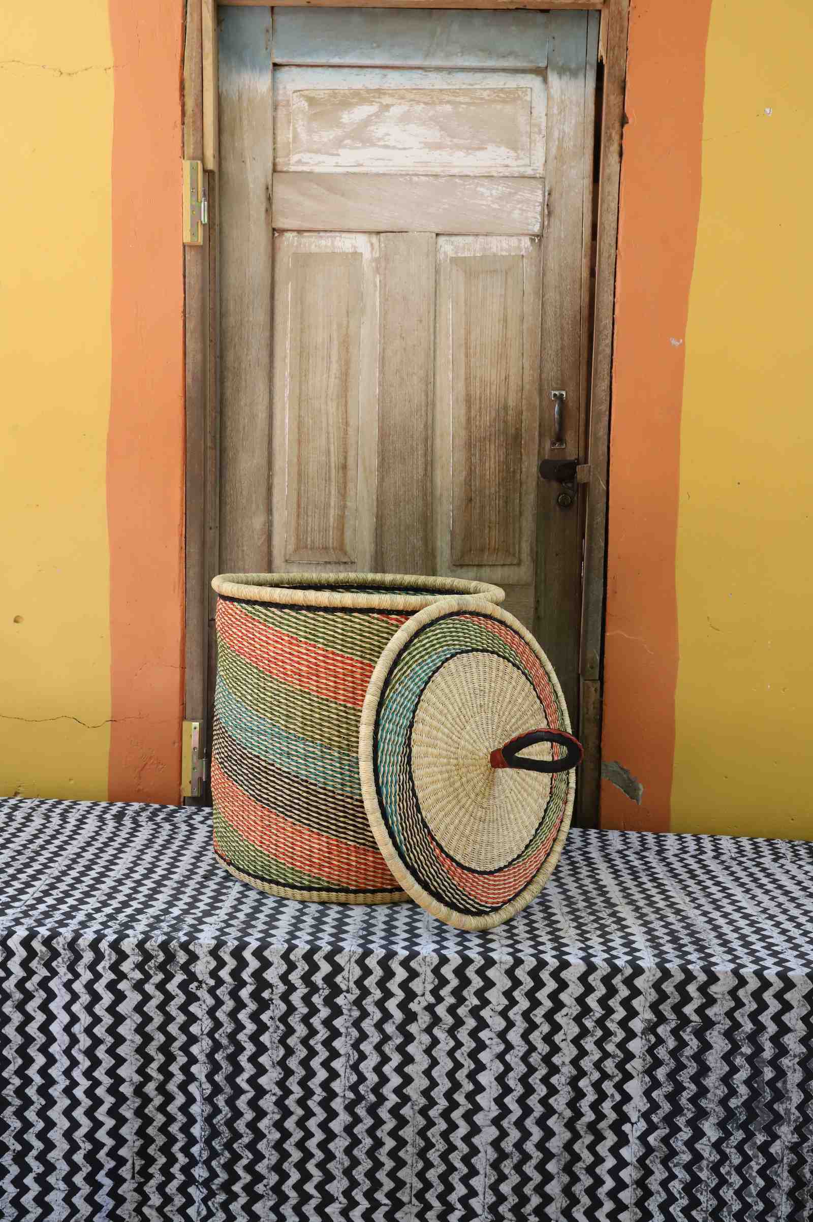 Handwoven Bolga laundry basket with lid removed, natural body with fine multicolour diagonal stripes.