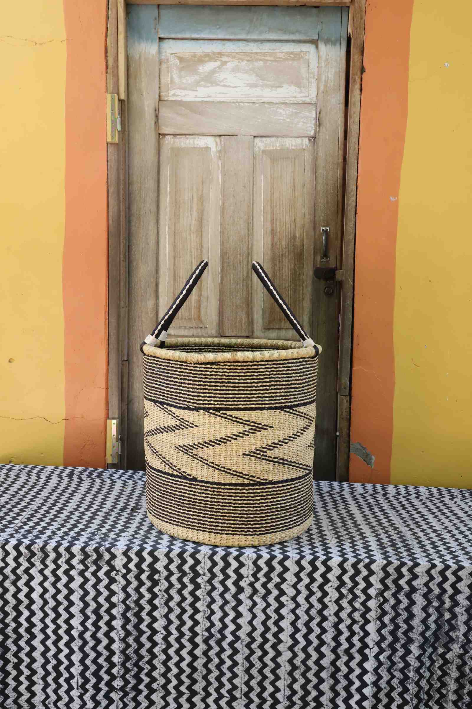 Large handwoven open-top Bolga laundry basket in natural straw with a fine black zigzag wave pattern.