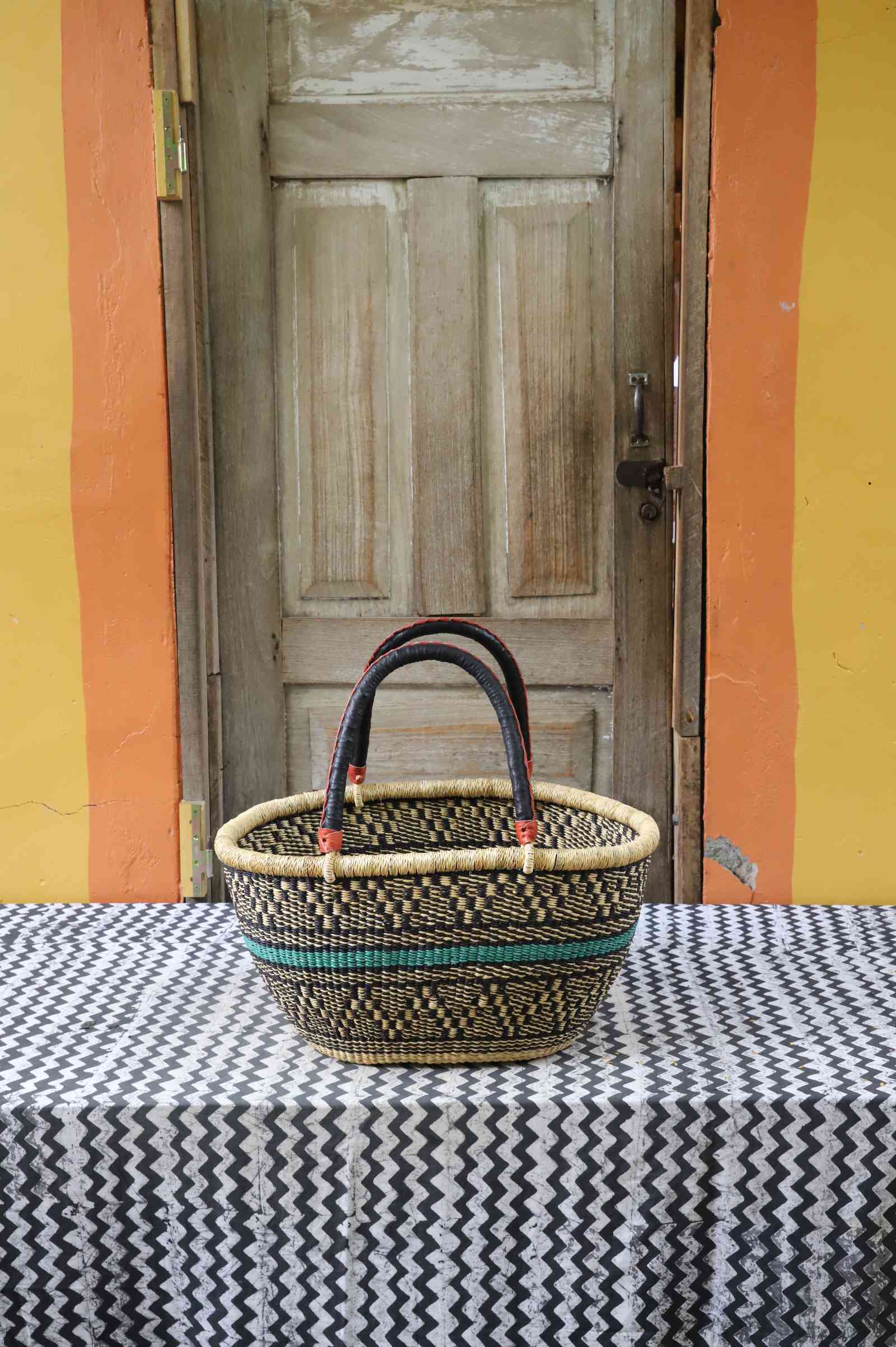 Large handwoven oval Bolga shopping basket in natural straw with a teal and orange banded accent.
