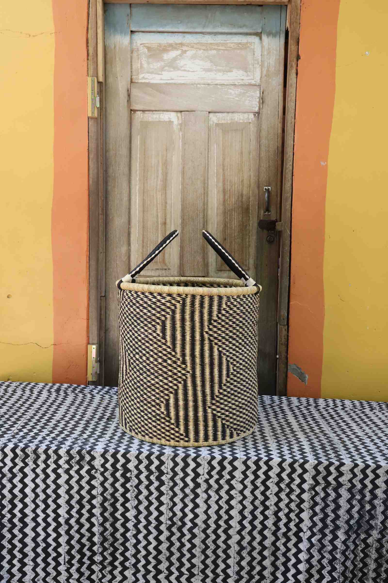 Large handwoven open-top Bolga laundry basket in natural straw with fine black diamond weave pattern.