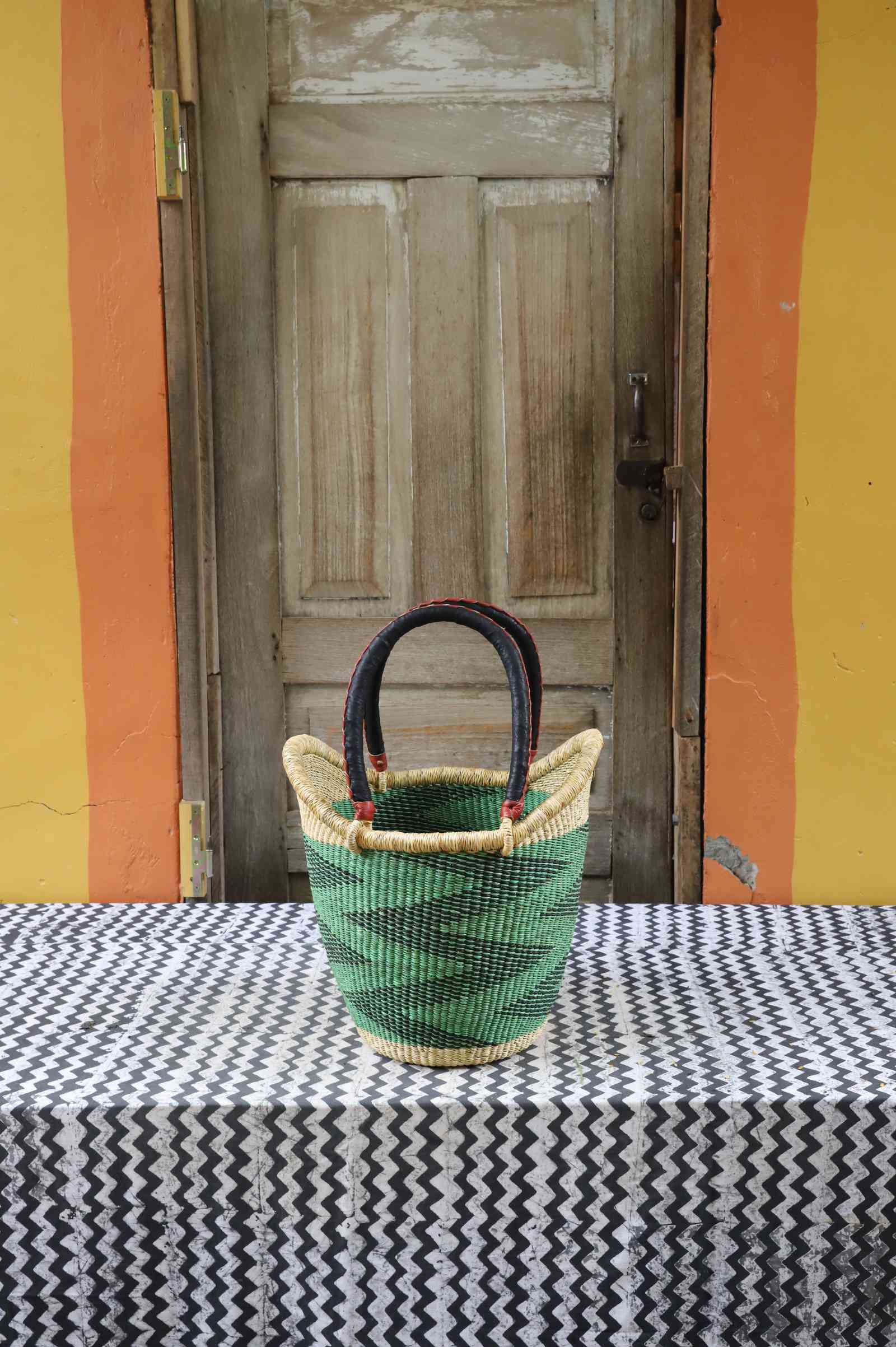 Medium handwoven Nyariga Bolga shopping basket in dyed green with a dark zigzag pattern and leather handles.