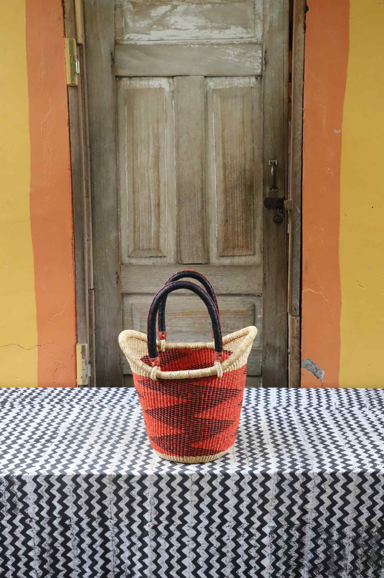 Small handwoven Nyariga Bolga shopping basket in rust-red with a dark zigzag pattern and dark handle.