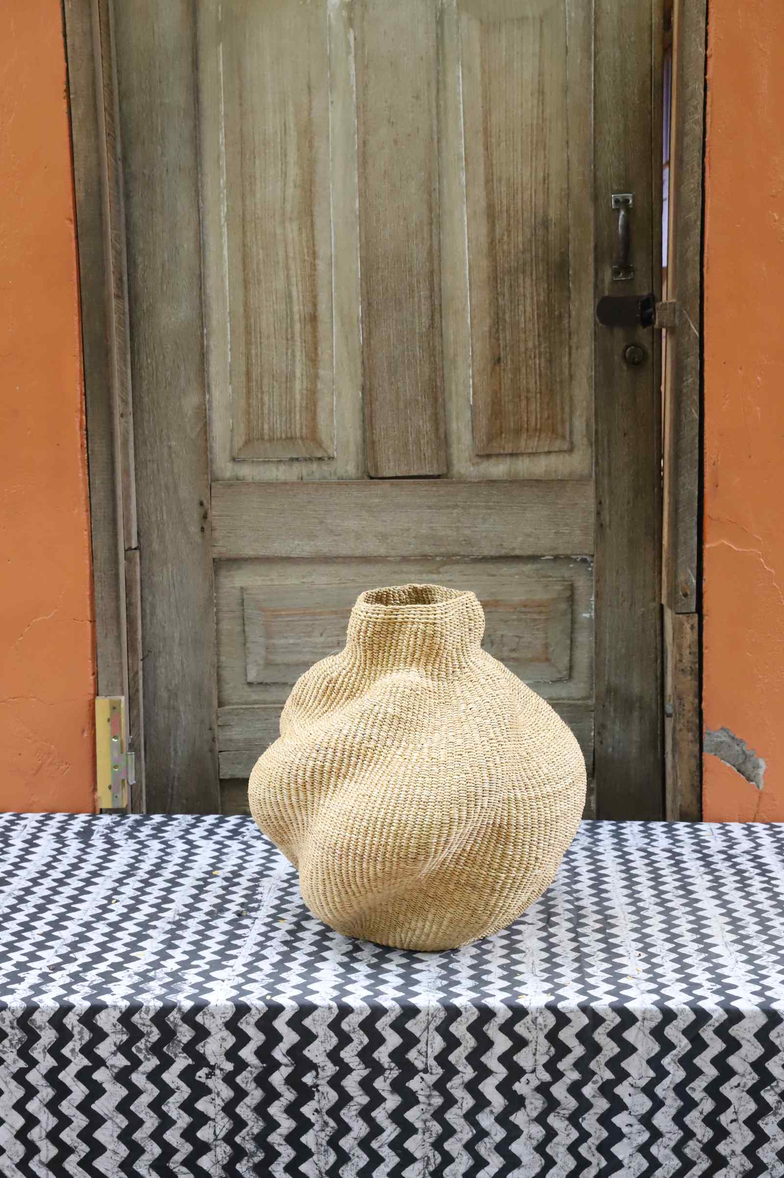 Handwoven Bolga art basket in an asymmetric sculpted form, all natural straw with a tight woven finish.