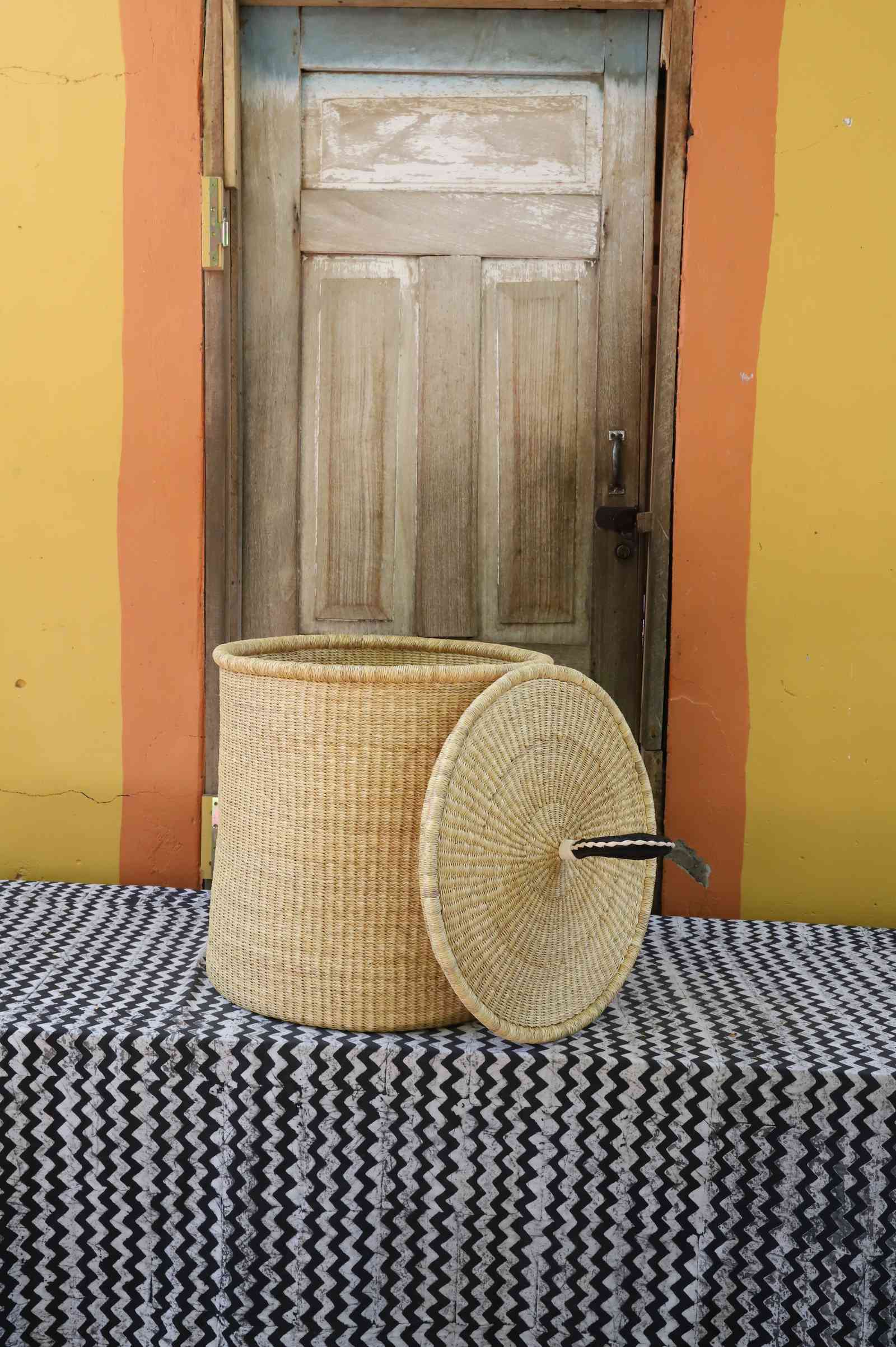 Handwoven Bolga laundry basket with lid removed, plain natural straw body with matching coiled lid.