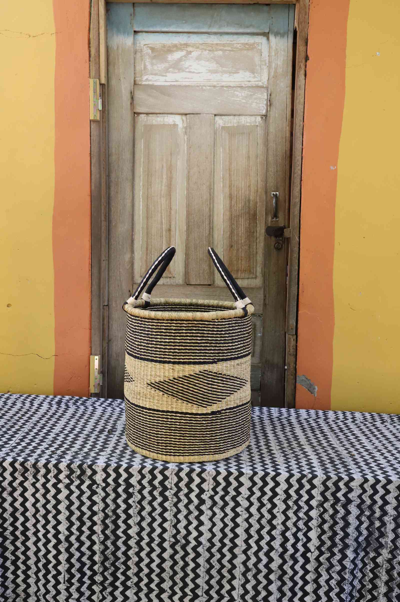 Large handwoven open-top Bolga laundry basket in natural straw with a dark diamond motif on the front.