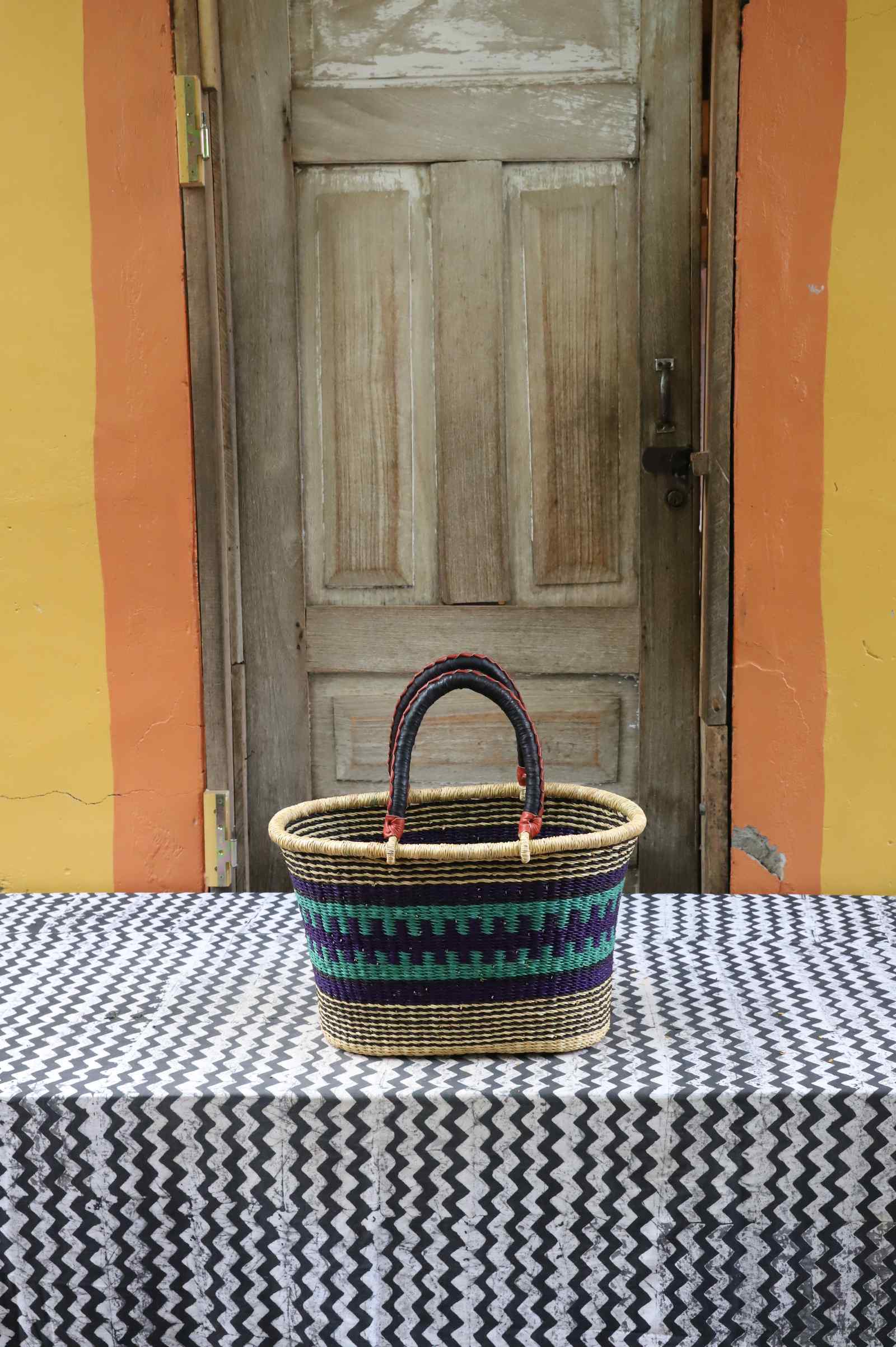 Medium handwoven Bolga Zaane Tia market basket in natural straw with teal, red and black fine banded stripes.