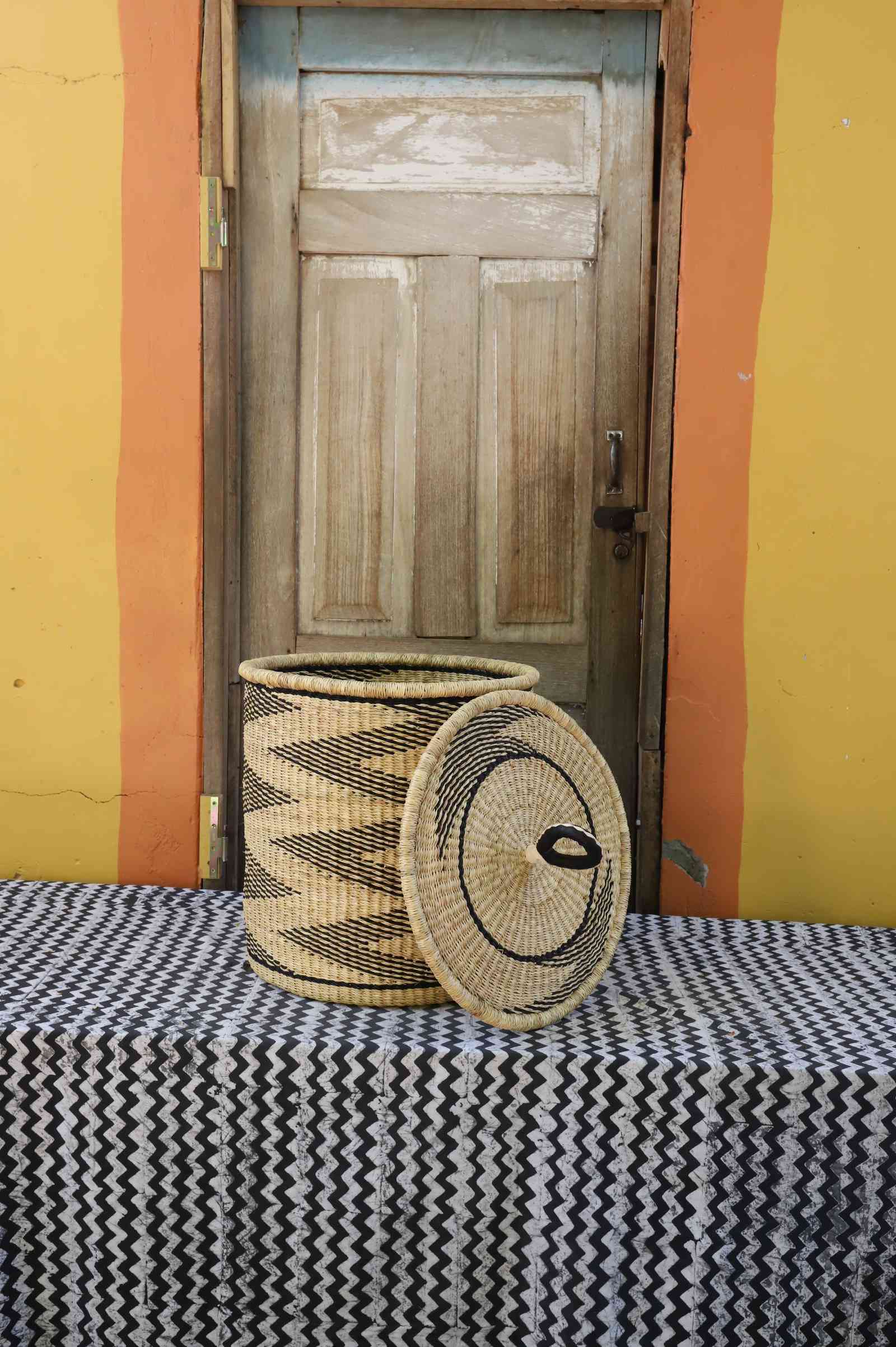 Handwoven Bolga laundry basket with lid removed, natural body with black wave motif and matching coiled lid.