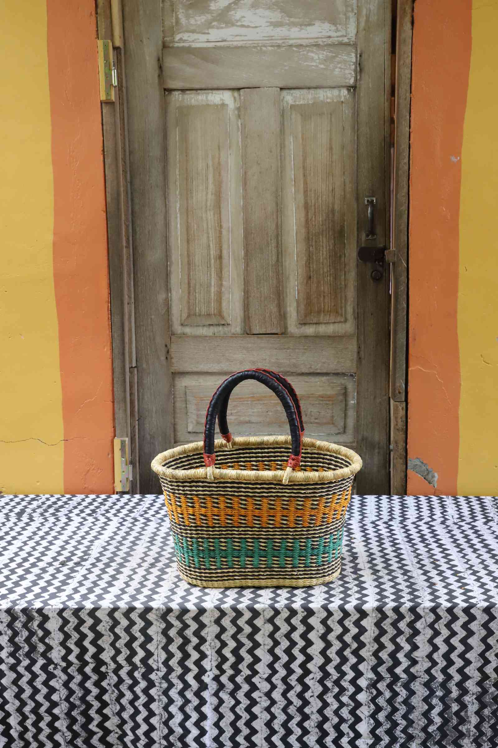 Medium handwoven Bolga Zaane Tia market basket in natural straw with fine orange, green and dark fine stripes.