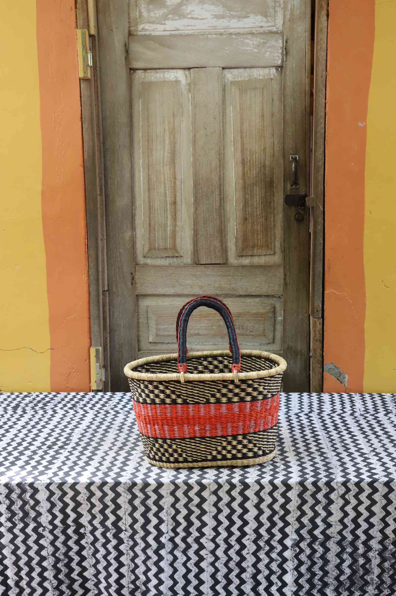 Medium handwoven Bolga Zaane Tia market basket in natural straw with a red and orange banded accent.