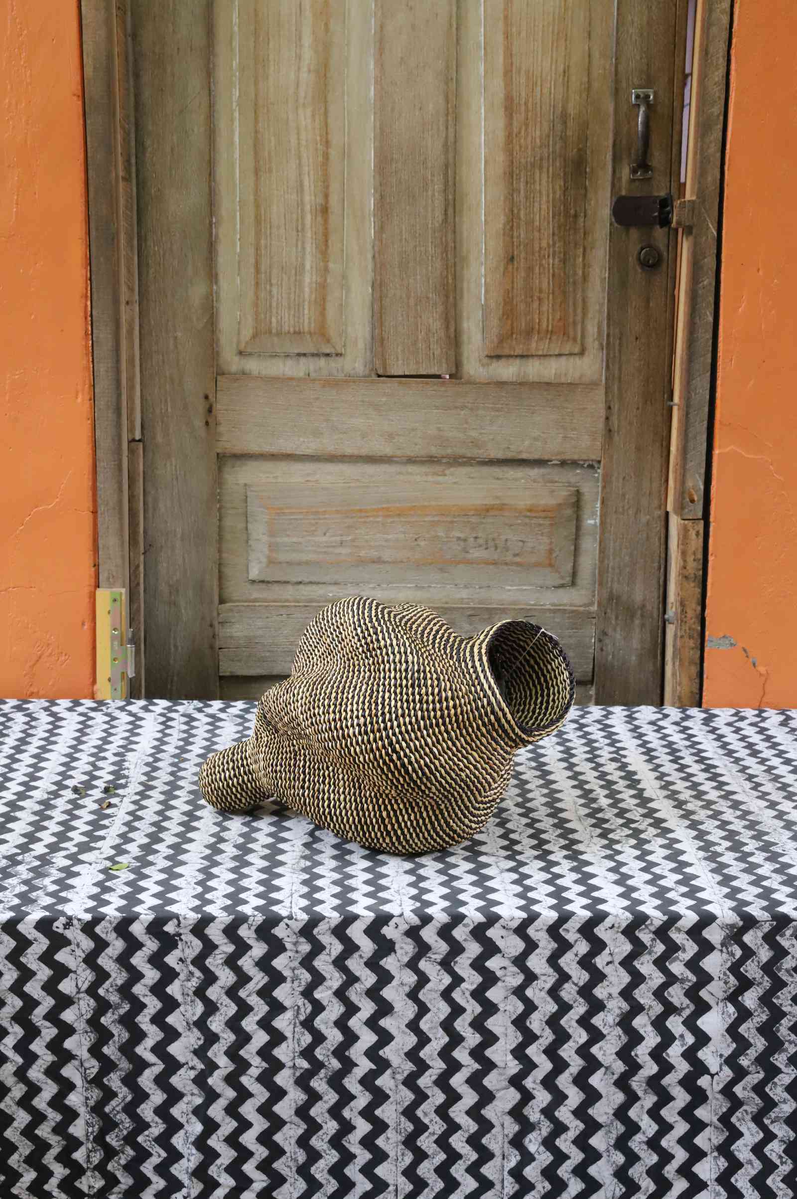 Small spiral-form Bolga art basket in natural straw, front view showing the curled tail detail.