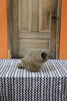Small spiral-form Bolga art basket in natural straw, front view showing the curled tail detail.